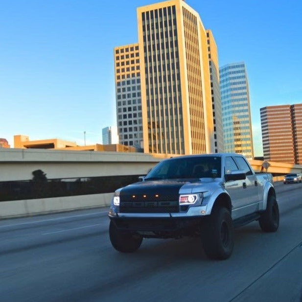2010-2016 Ford Raptor fenders installed on a truck driving through a cityscape, showcasing rugged off-road style.