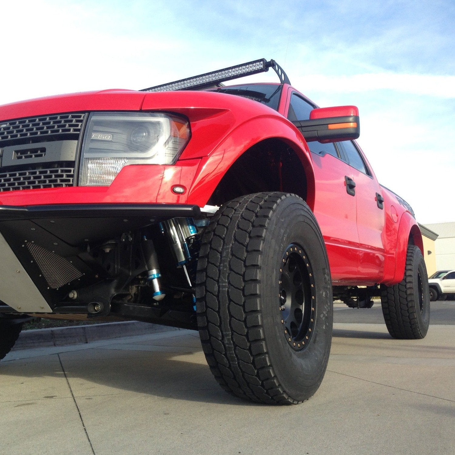 2010-2016 Ford Raptor fenders showcasing a lifted red truck with offroad tires and enhanced suspension.