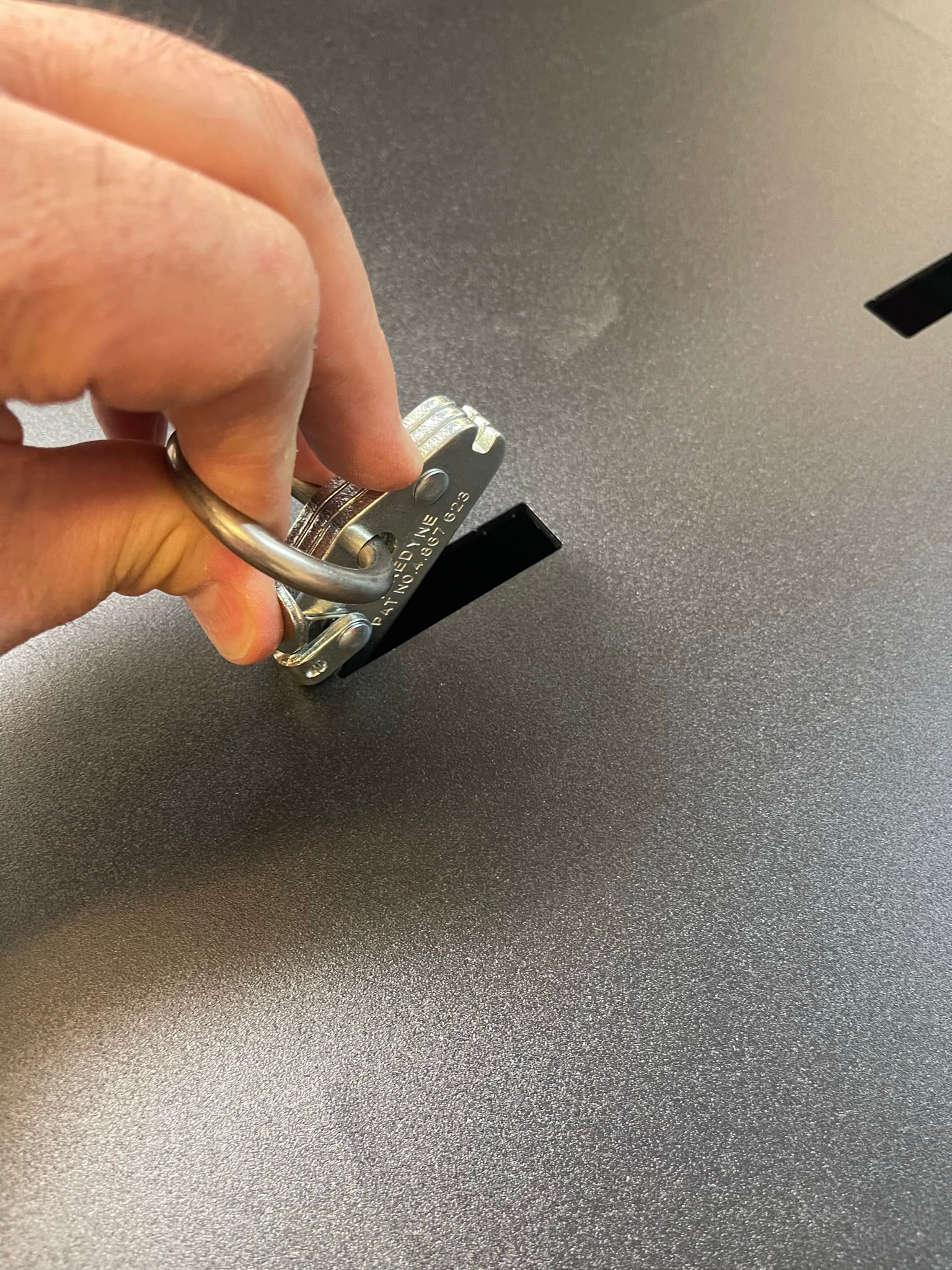 Hand holding a lock over a slot on a textured surface of a 2017-2024 Raptor rear bed organizer with cargo slide tray.