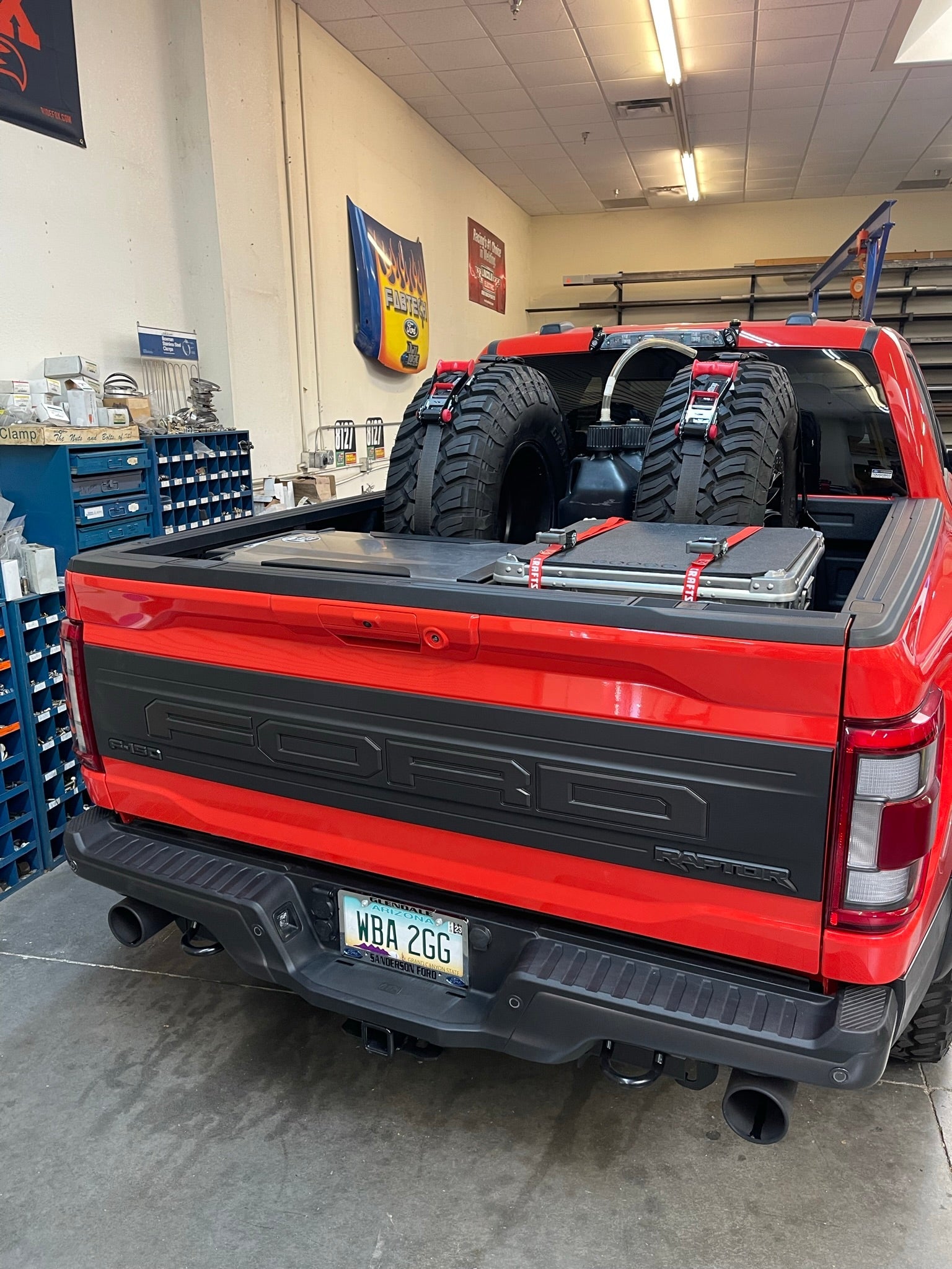 Raptor rear bed organizer with cargo slide tray in a truck bed, featuring mounted offroad tires and tools.