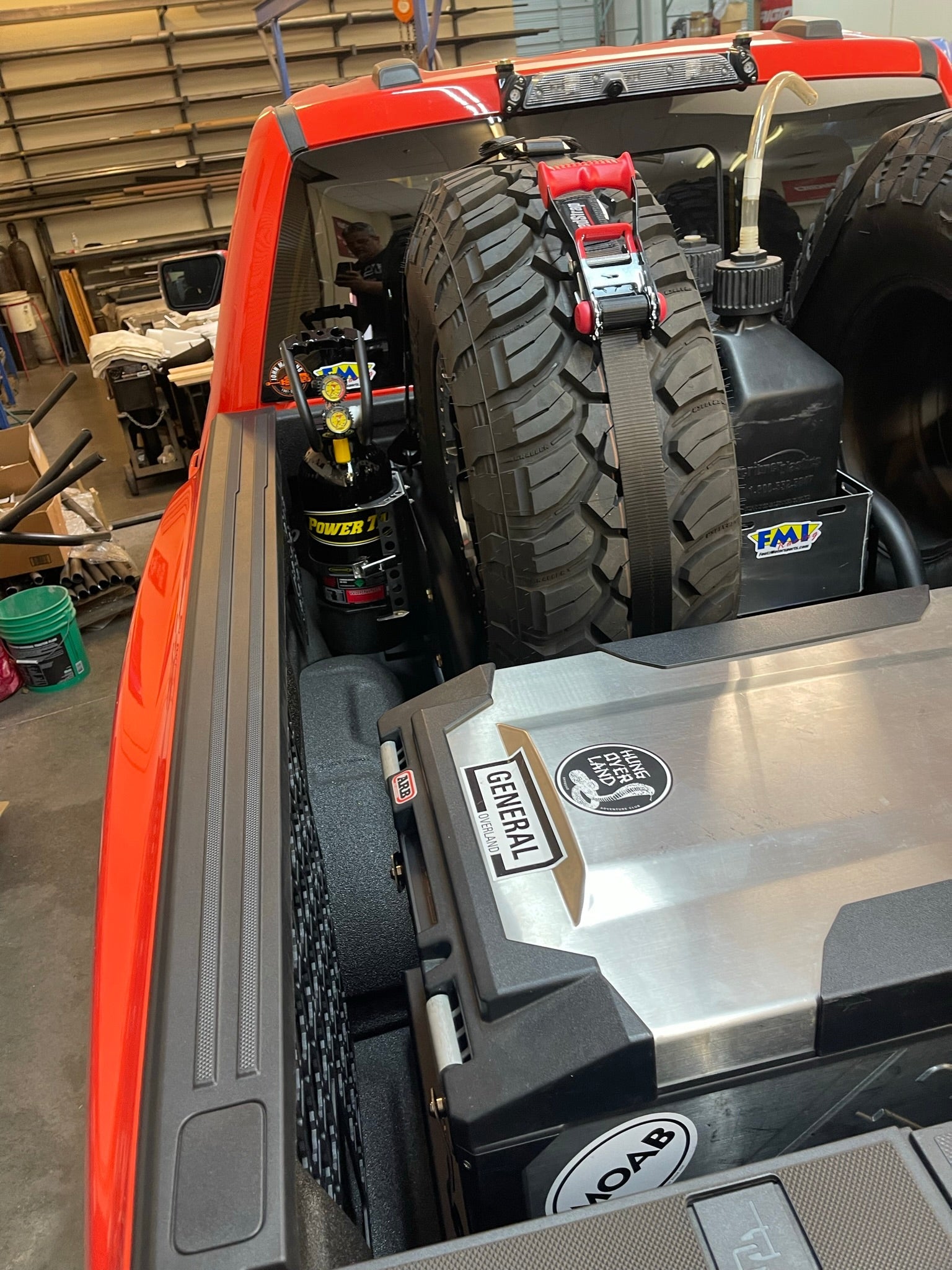 Raptor rear bed organizer with cargo slide tray, featuring tools, spare tire, and storage for offroad gear.