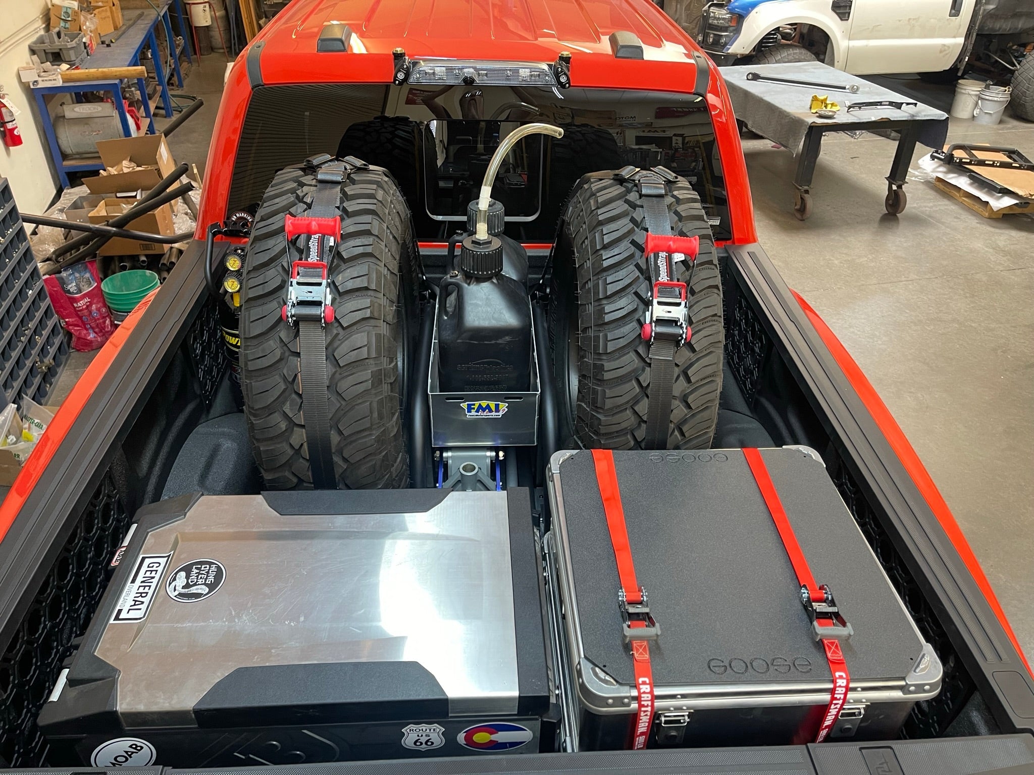 Rear view of a 2017-2024 Raptor truck bed featuring a cargo slide tray with organized storage for tires and gear.