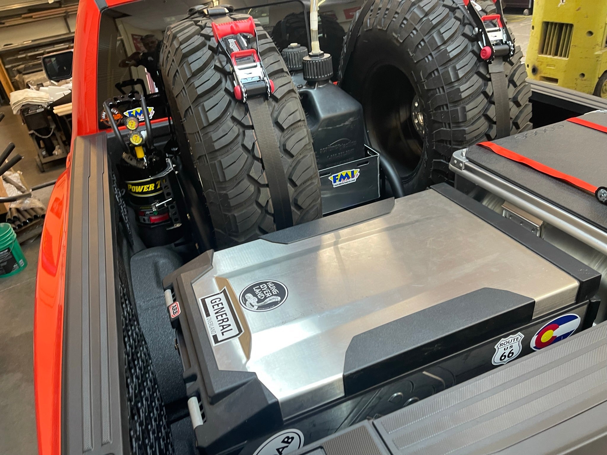 Raptor rear bed organizer with cargo slide tray, featuring storage for tires, tools, and equipment in a truck bed.
