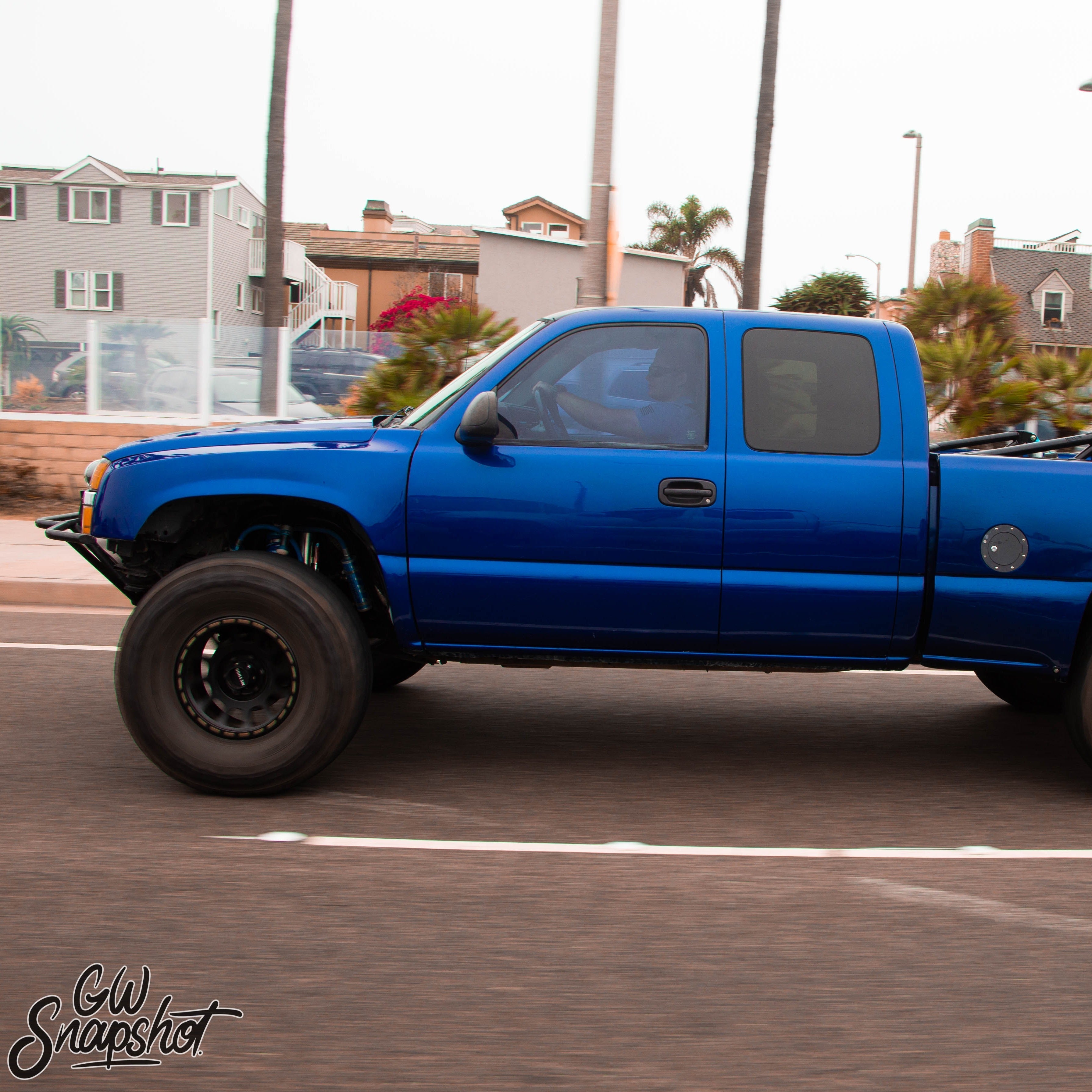 2003-2006 Chevrolet Silverado fenders on a blue truck driving on a coastal road, showcasing offroad capabilities.