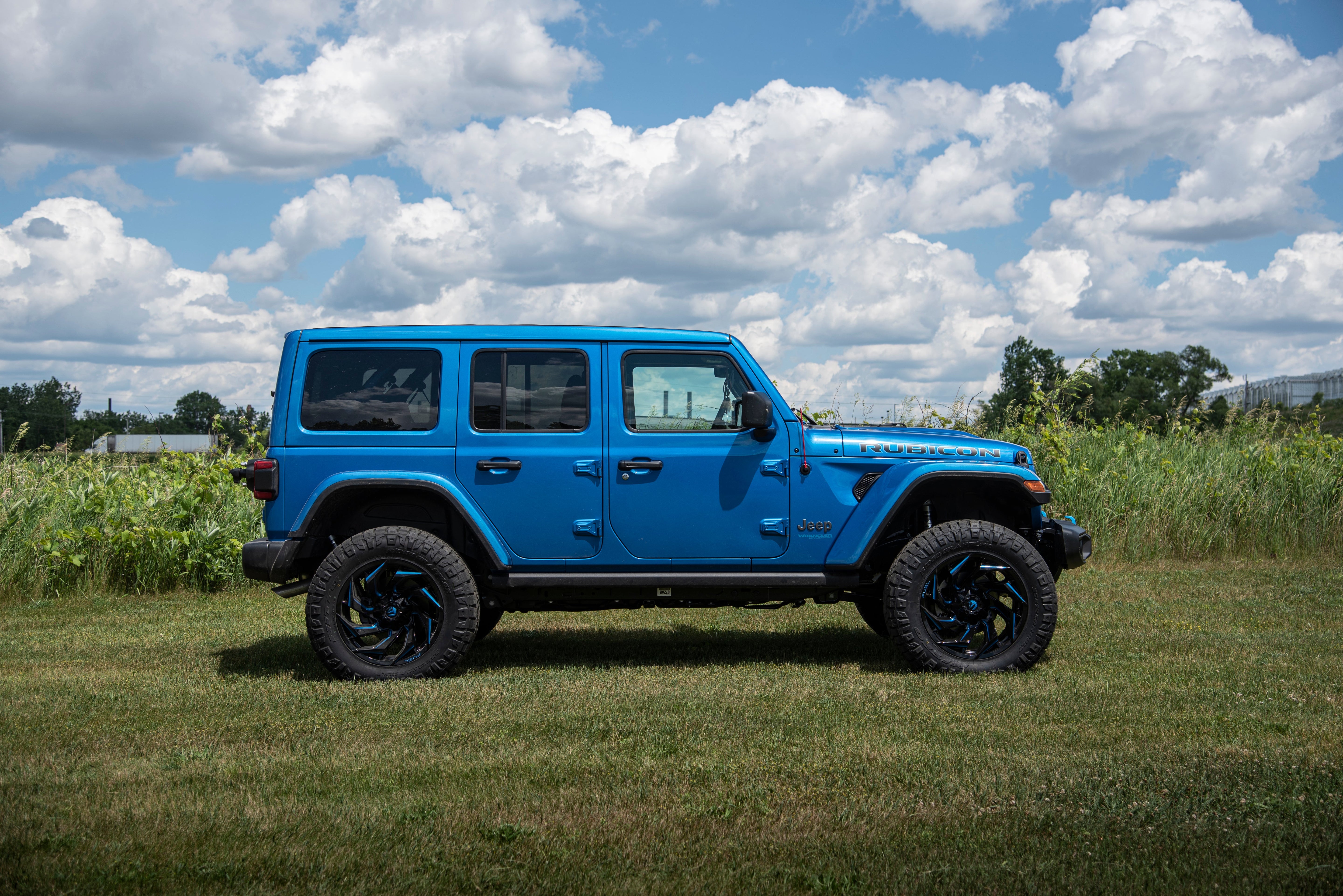 3-inch lift kit for Jeep Wrangler JL 4xe, showcasing a blue 4-door model with off-road tires in a grassy field.
