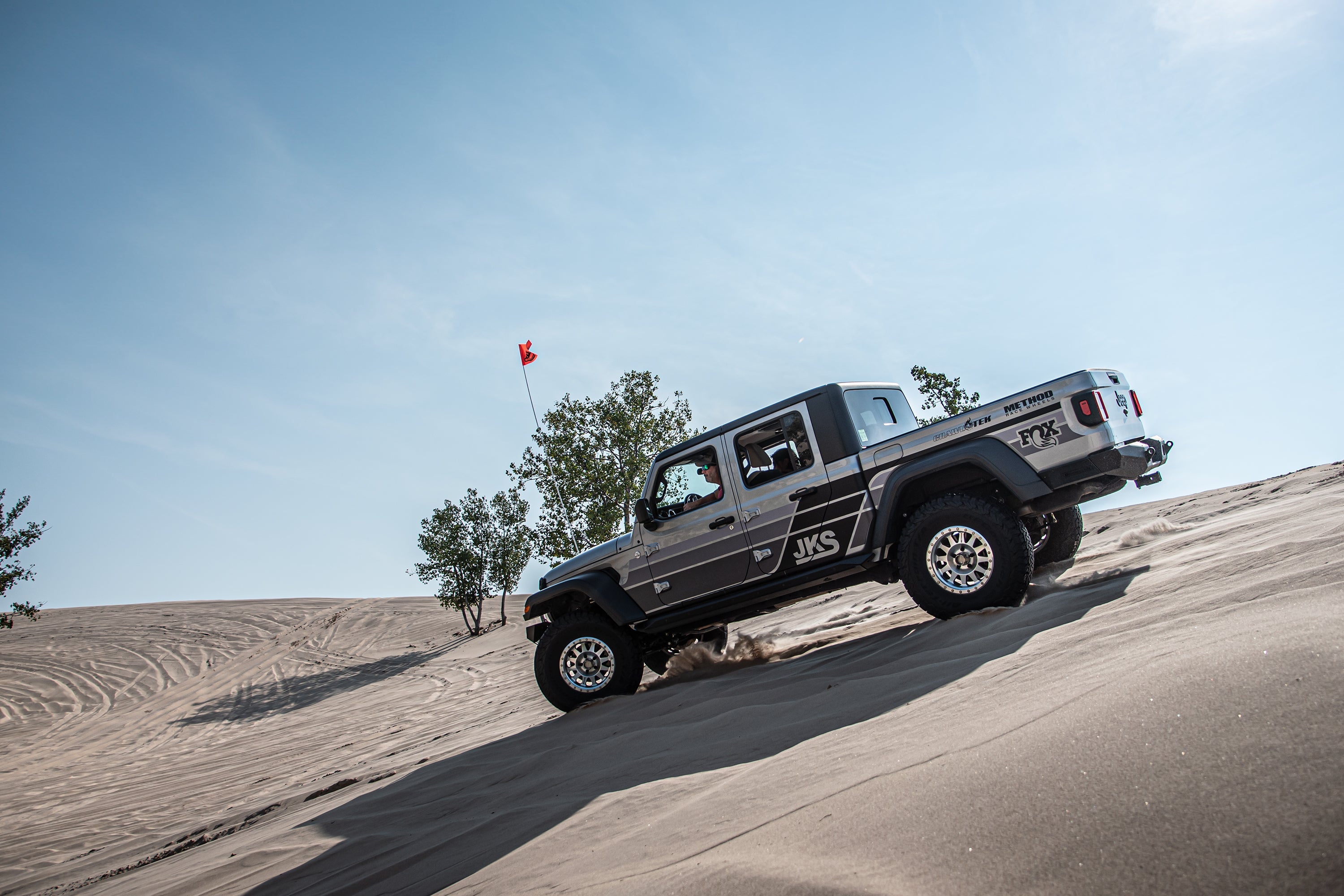 3.5-inch lift kit for Gladiator JT shown on a truck climbing a sandy dune, showcasing off-road capabilities.