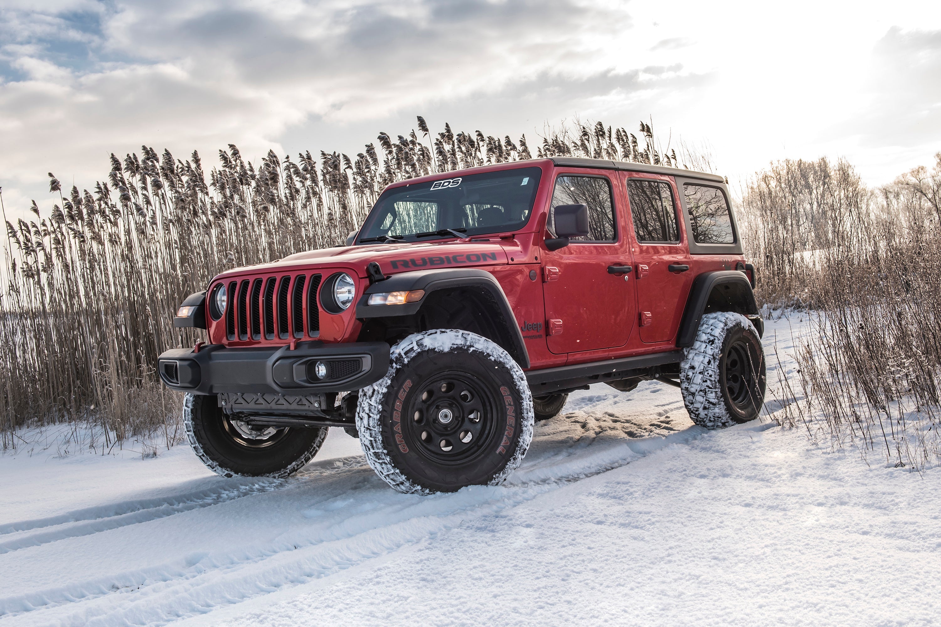 Red Jeep Wrangler JL 4-Door with a 2-inch lift kit parked in snowy terrain, showcasing enhanced off-road capabilities.