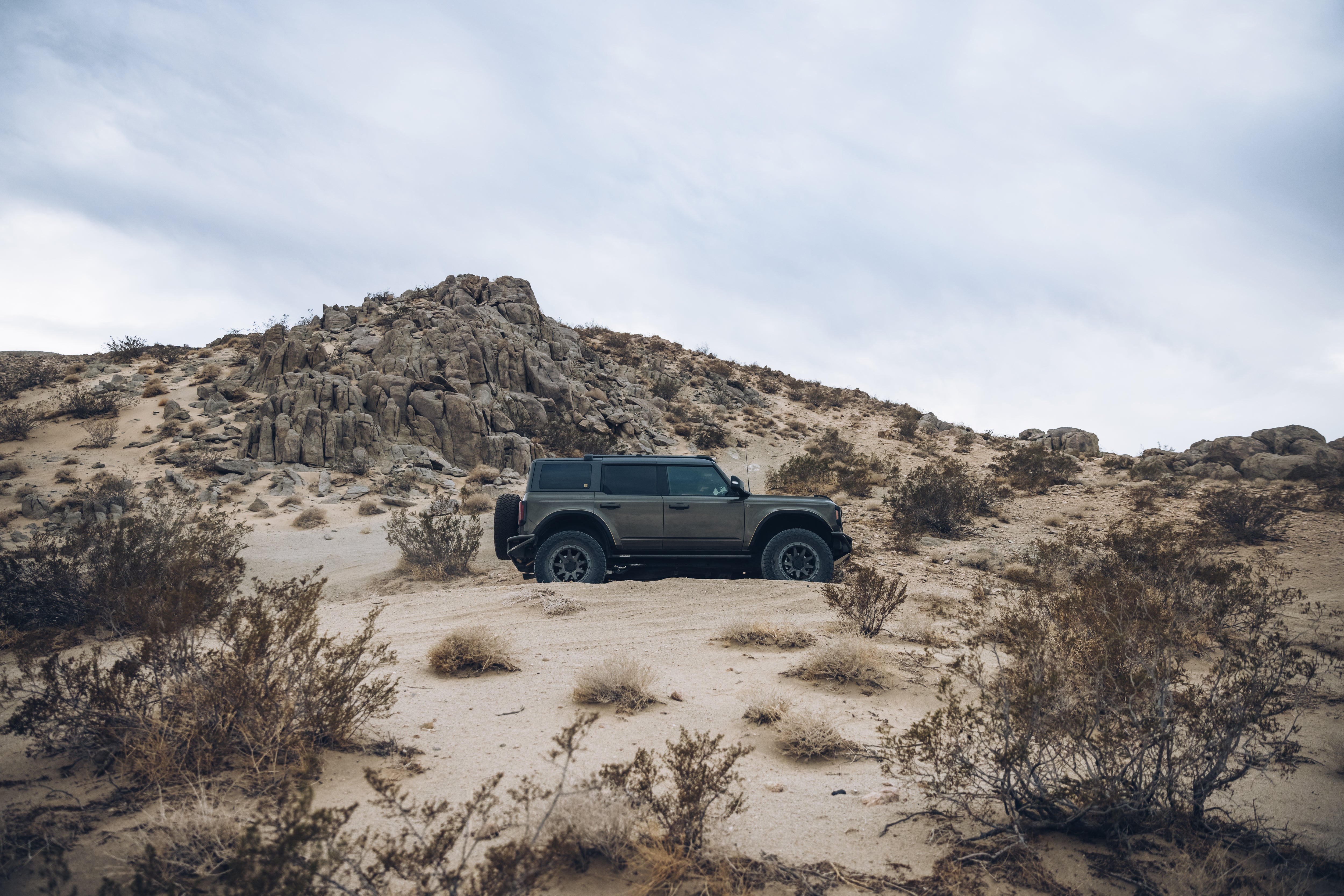 2021 Outer Banks vehicle by BAJA FORGED navigating a rugged desert landscape with rocky terrain and sparse vegetation.