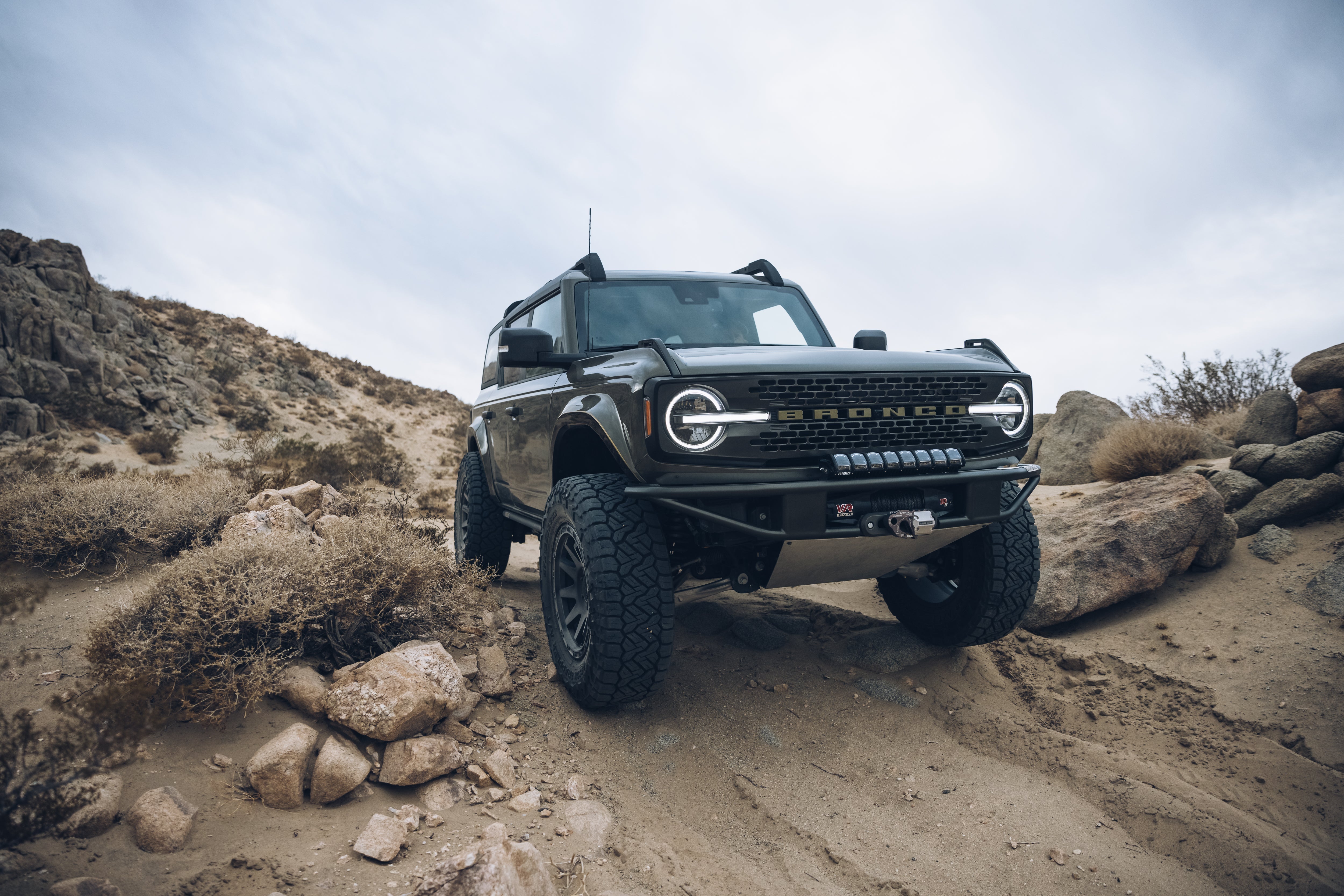 2021 Ford Bronco Outer Banks with BAJA FORGED accessories on rugged terrain, showcasing offroad capability and style.