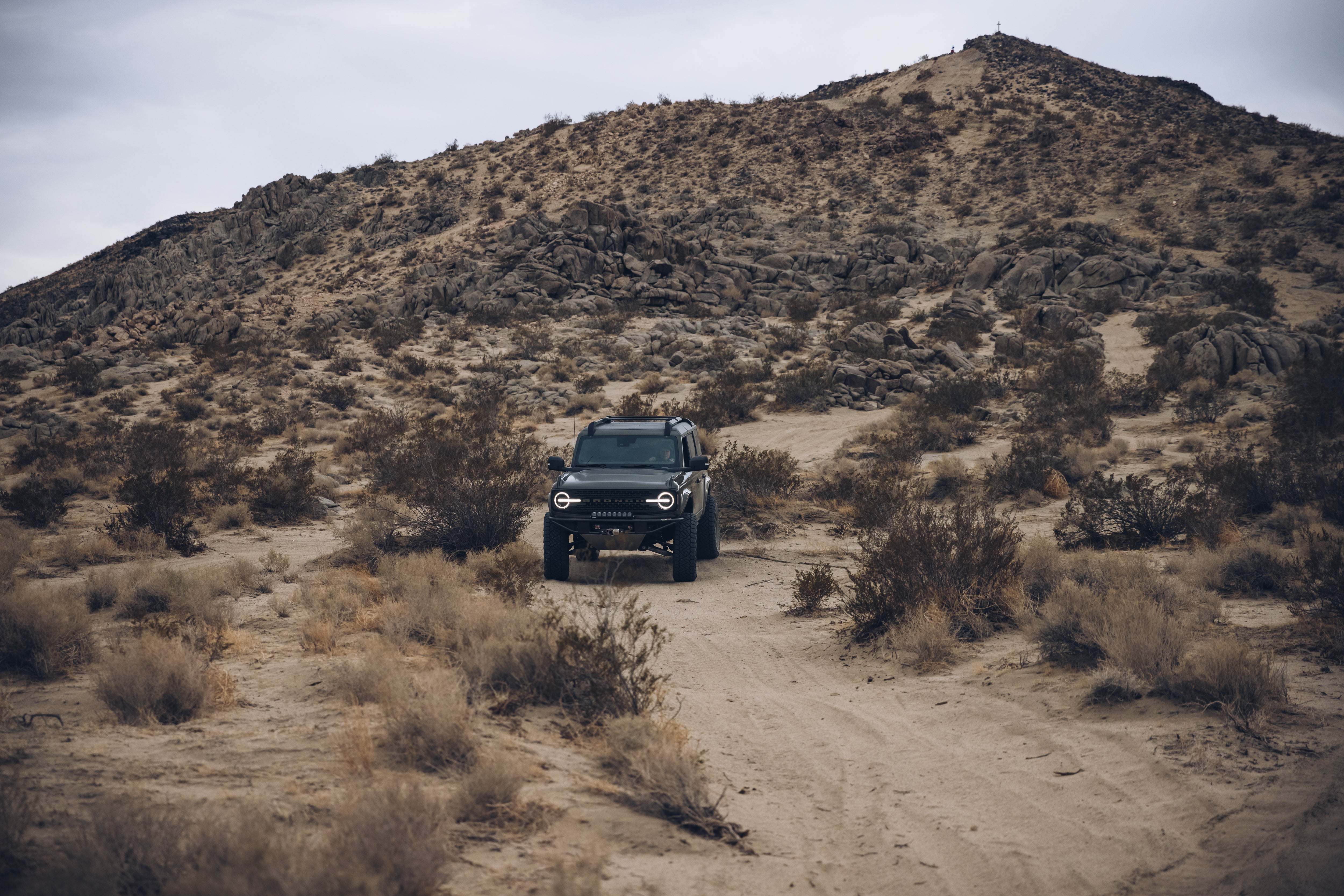 2021 Outer Banks BAJA FORGED off-road vehicle navigating a rugged desert landscape with rocky hills in the background.