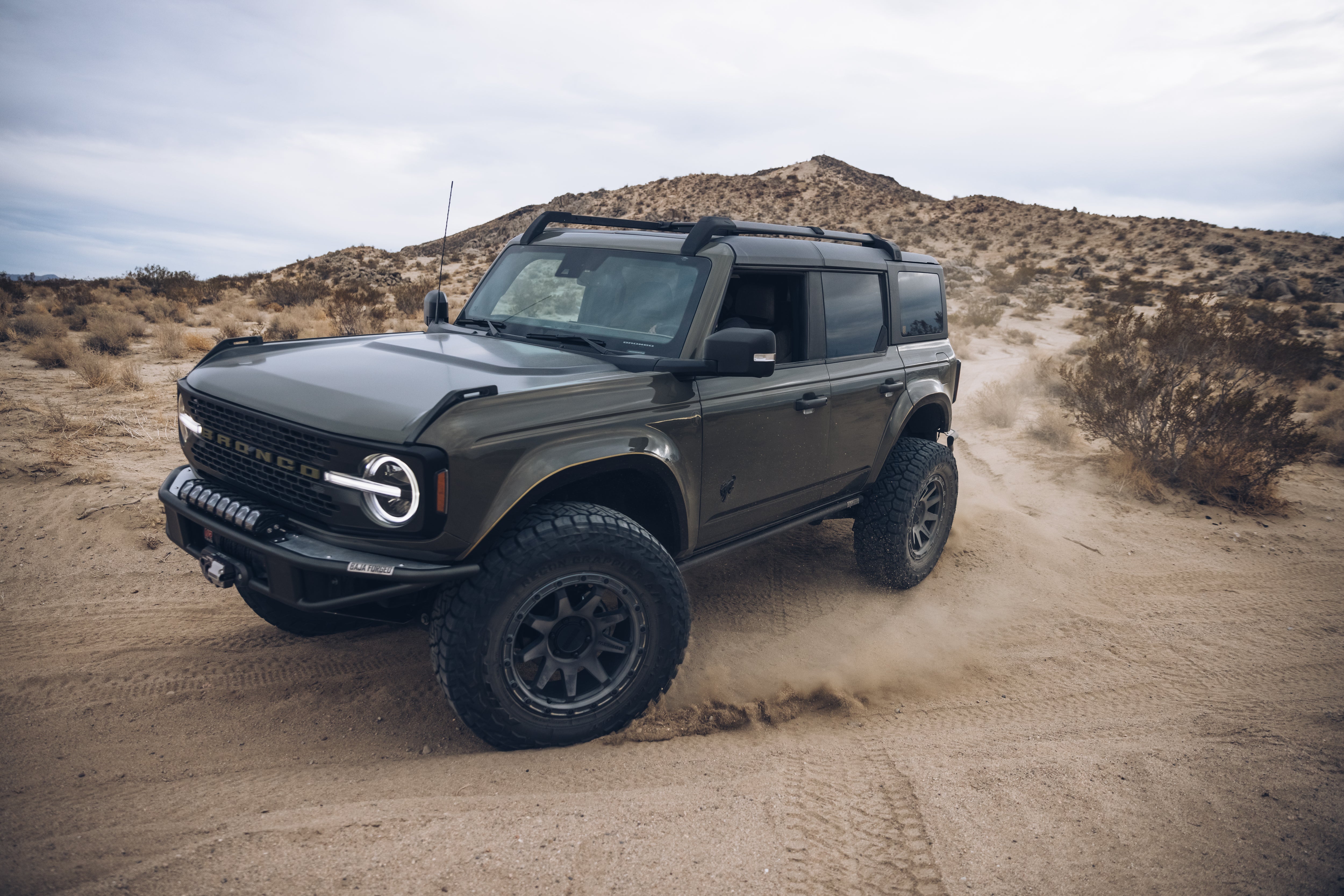 2021 Outer Banks Bronco with BAJA FORGED accessories driving through sandy terrain, showcasing offroad capabilities.
