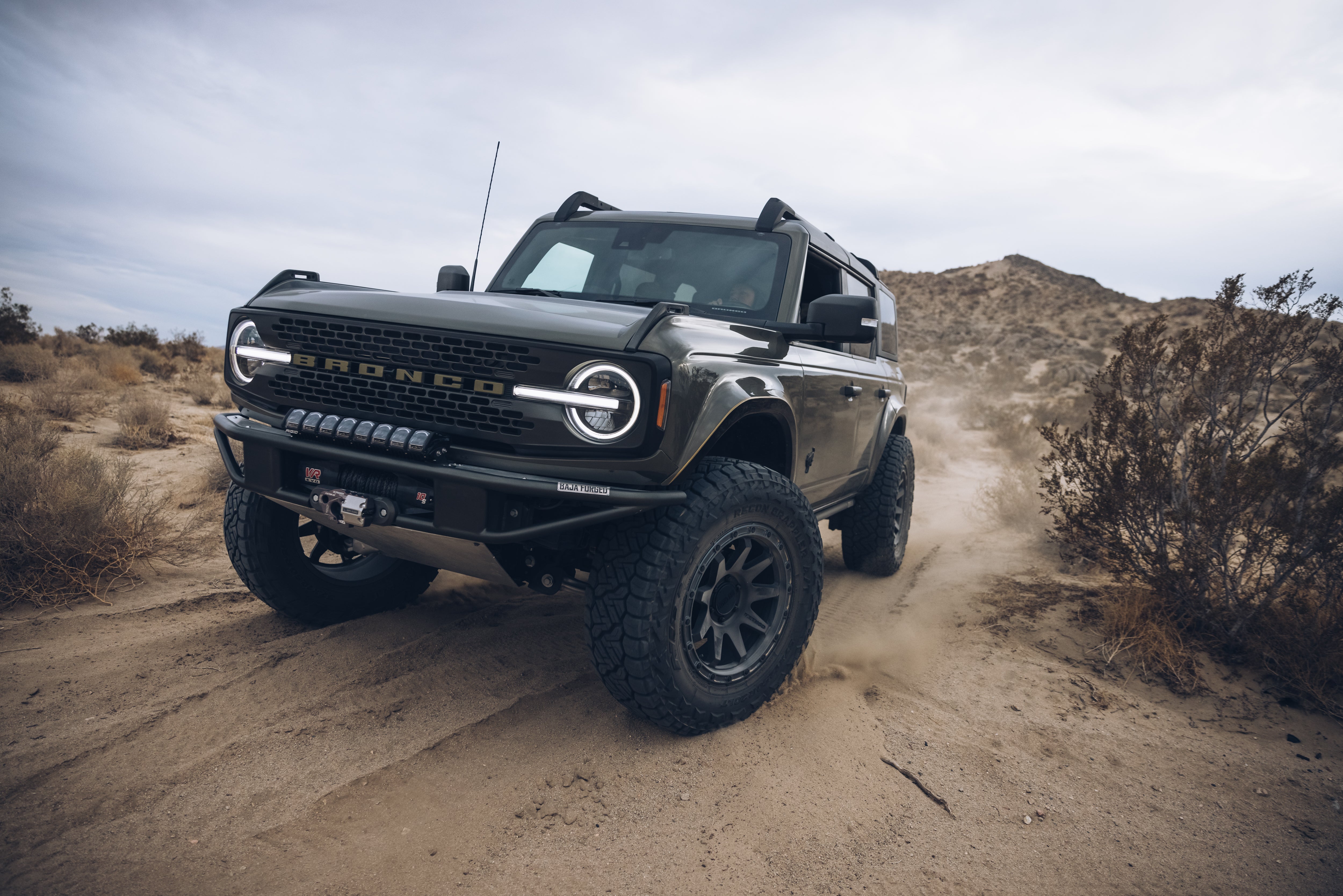 2021 Outer Banks Bronco with BAJA FORGED accessories driving on sandy terrain, showcasing rugged off-road capabilities.