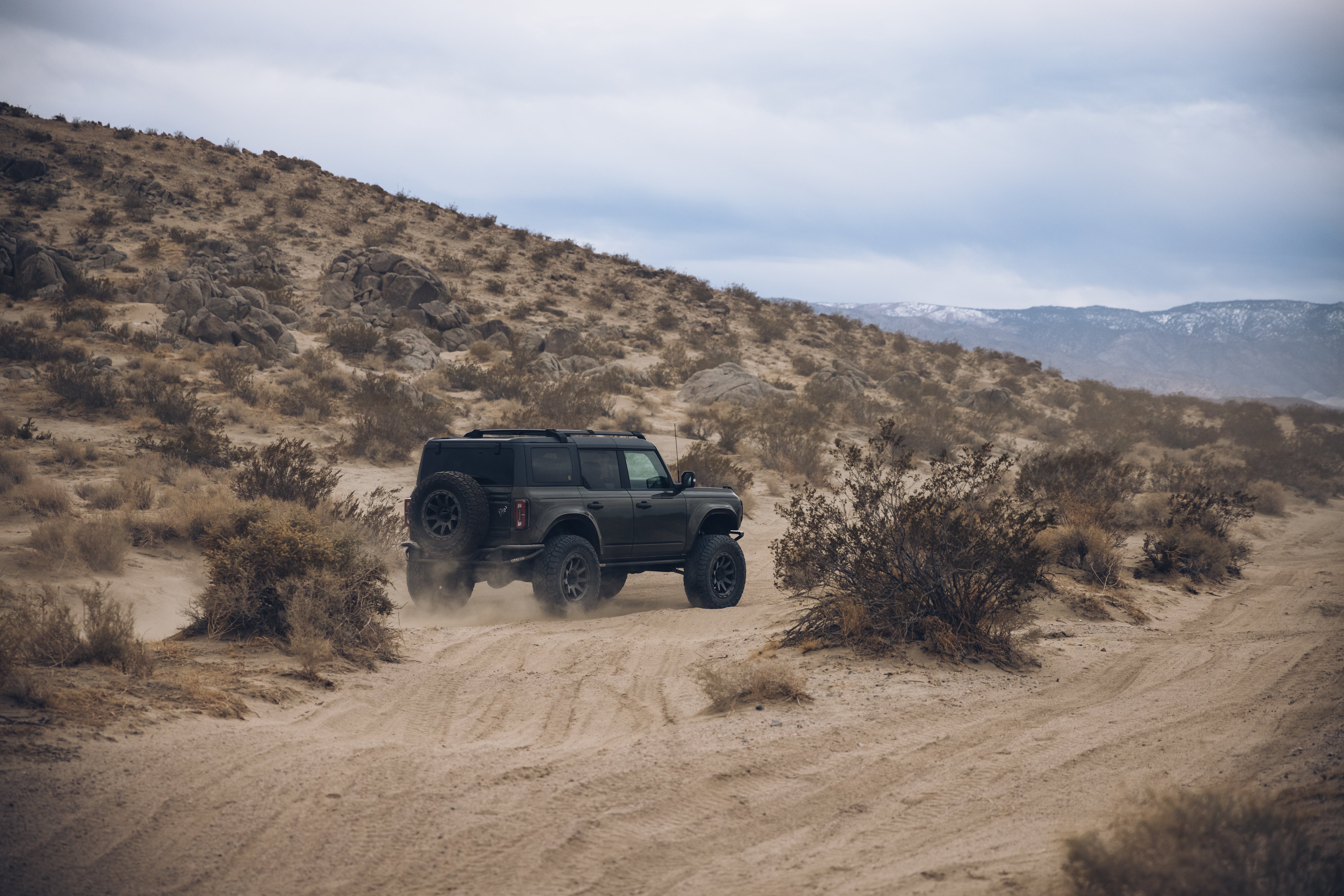 2021 Outer Banks BAJA FORGED off-road vehicle navigating a sandy desert landscape with rocky hills in the background.
