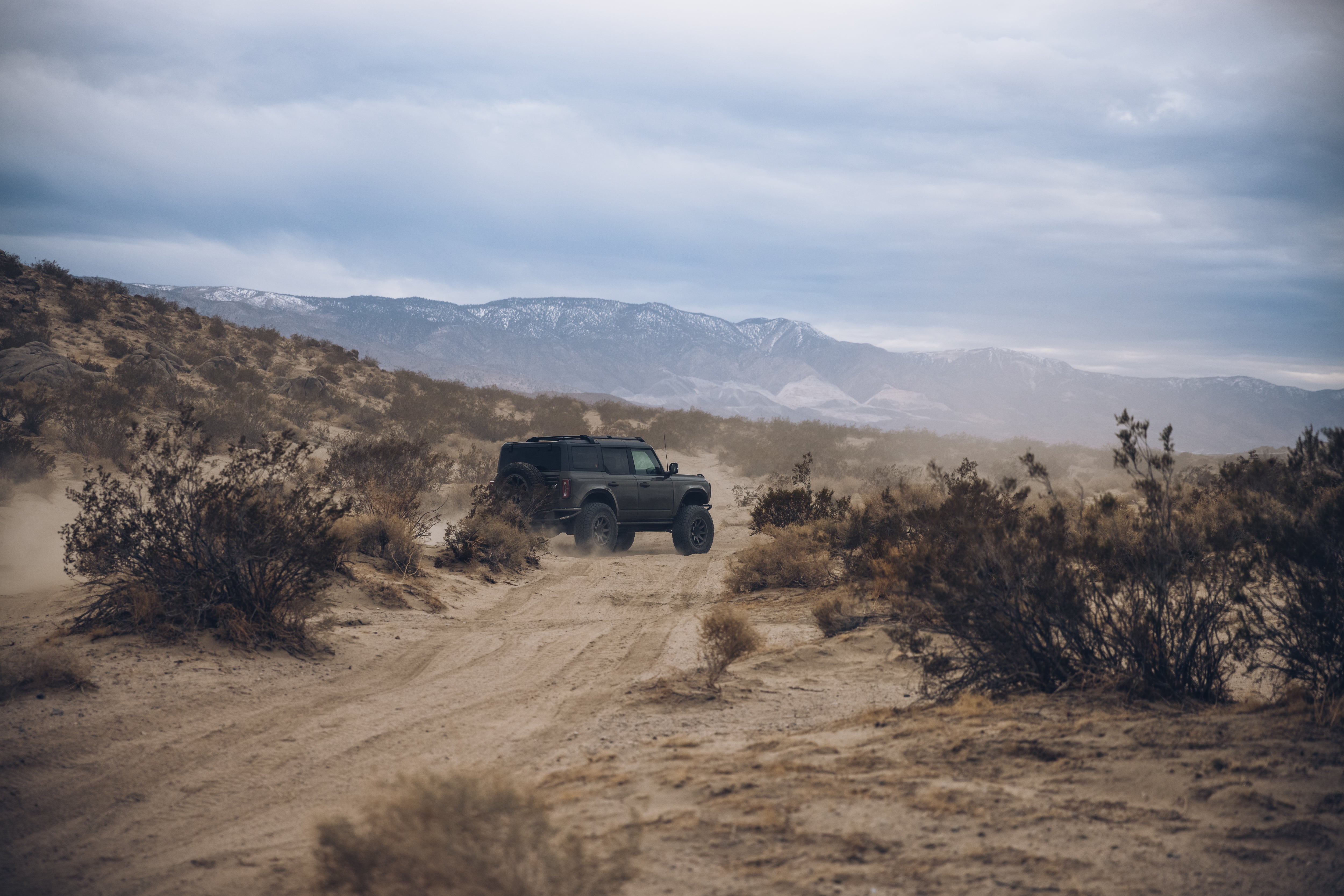 2021 Outer Banks BAJA FORGED vehicle navigating a rugged desert landscape with mountains in the background.