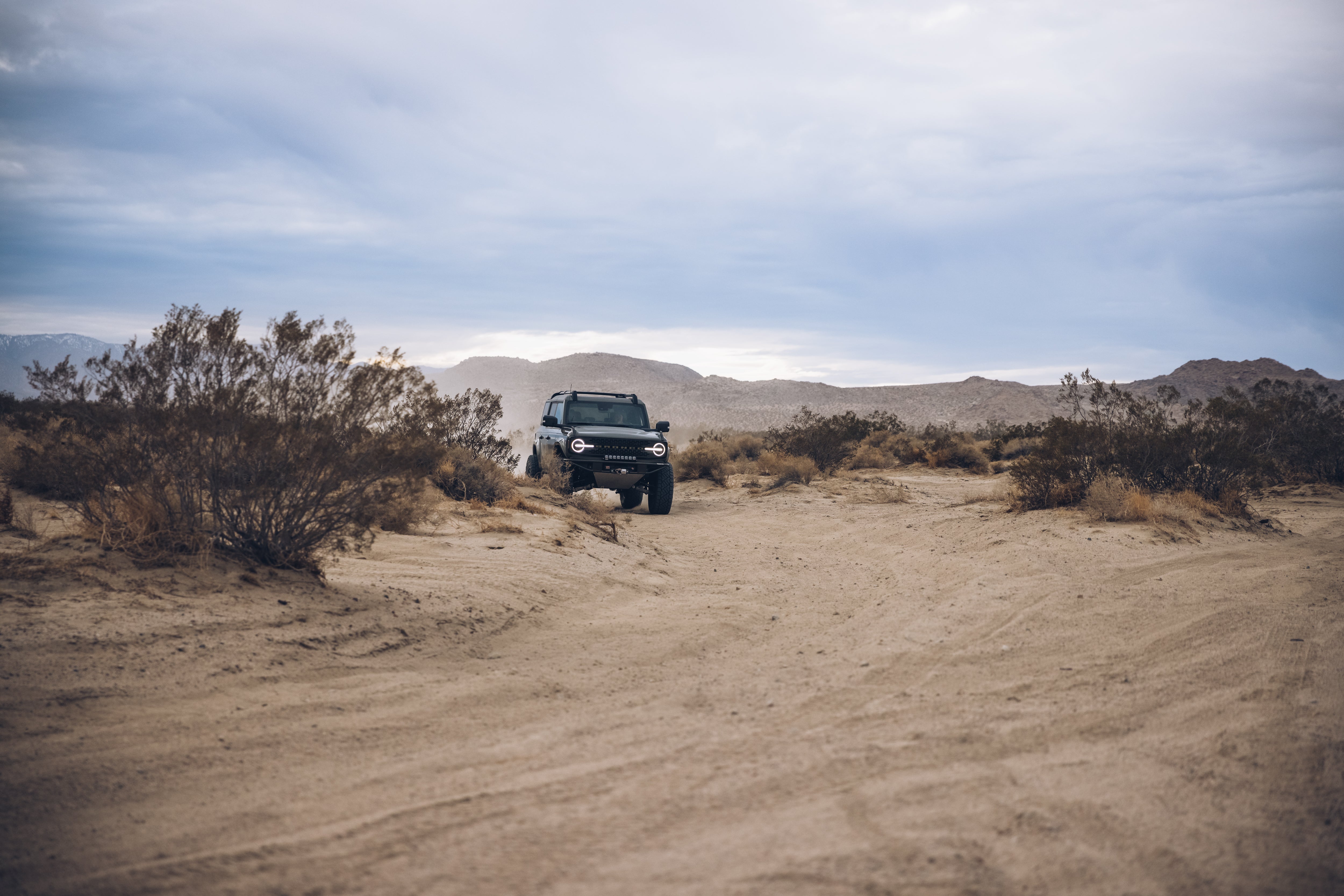 2021 Outer Banks BAJA FORGED off-road vehicle navigating a sandy desert landscape with rugged terrain and sparse vegetation.