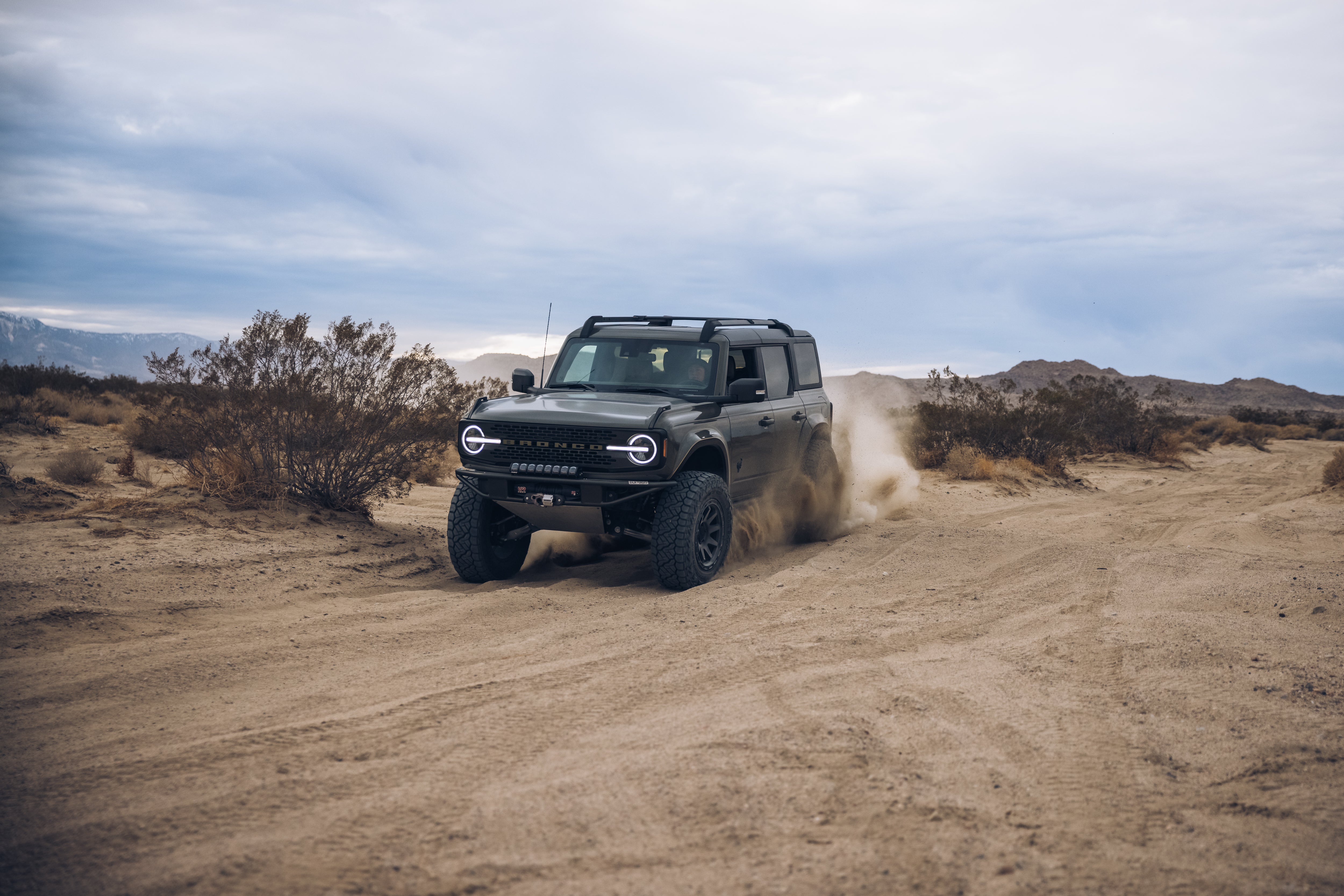 2021 Outer Banks Bronco by BAJA FORGED driving through sandy terrain, showcasing off-road capabilities and rugged design.