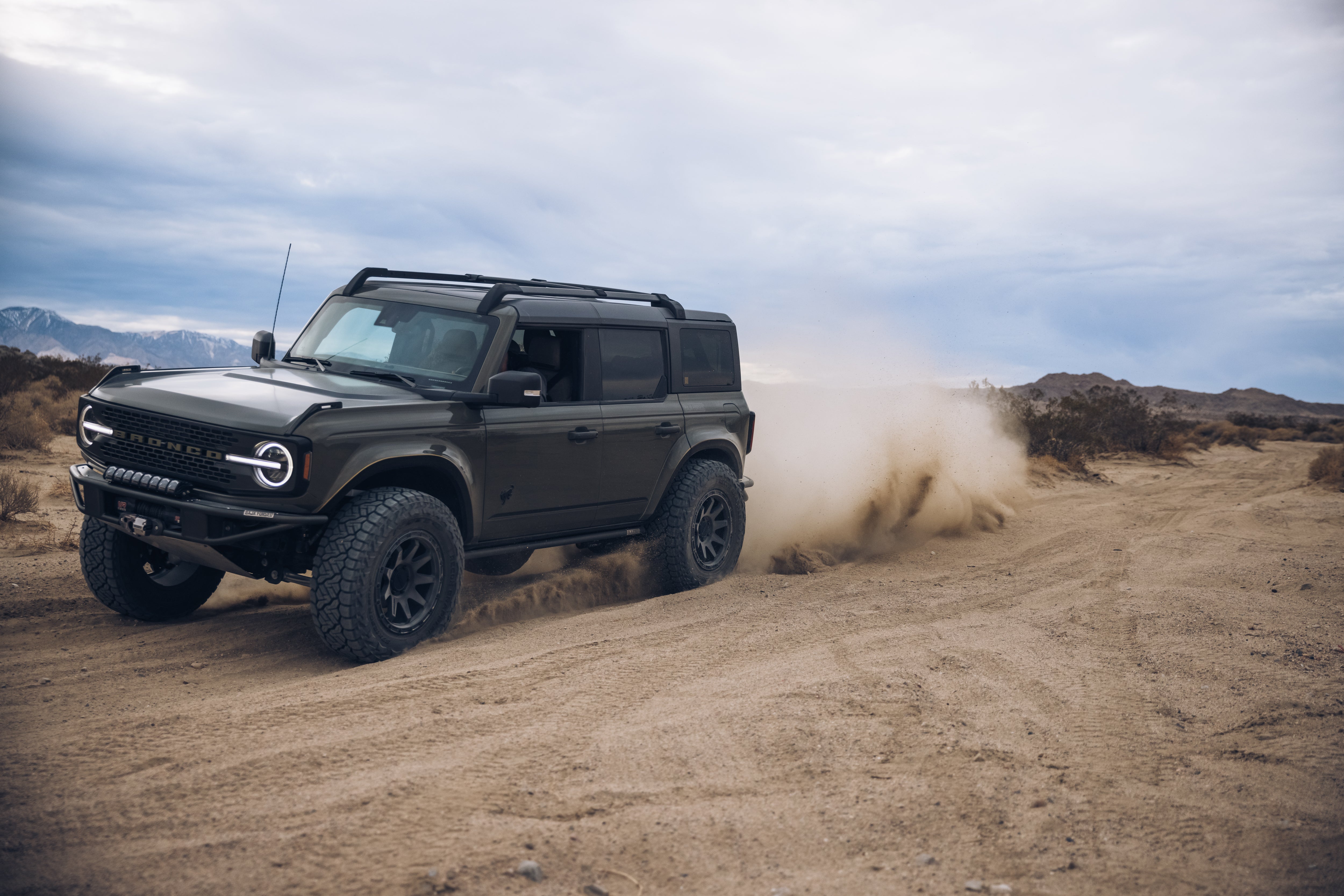 2021 Outer Banks Bronco by BAJA FORGED driving through sandy terrain, showcasing rugged off-road capabilities.