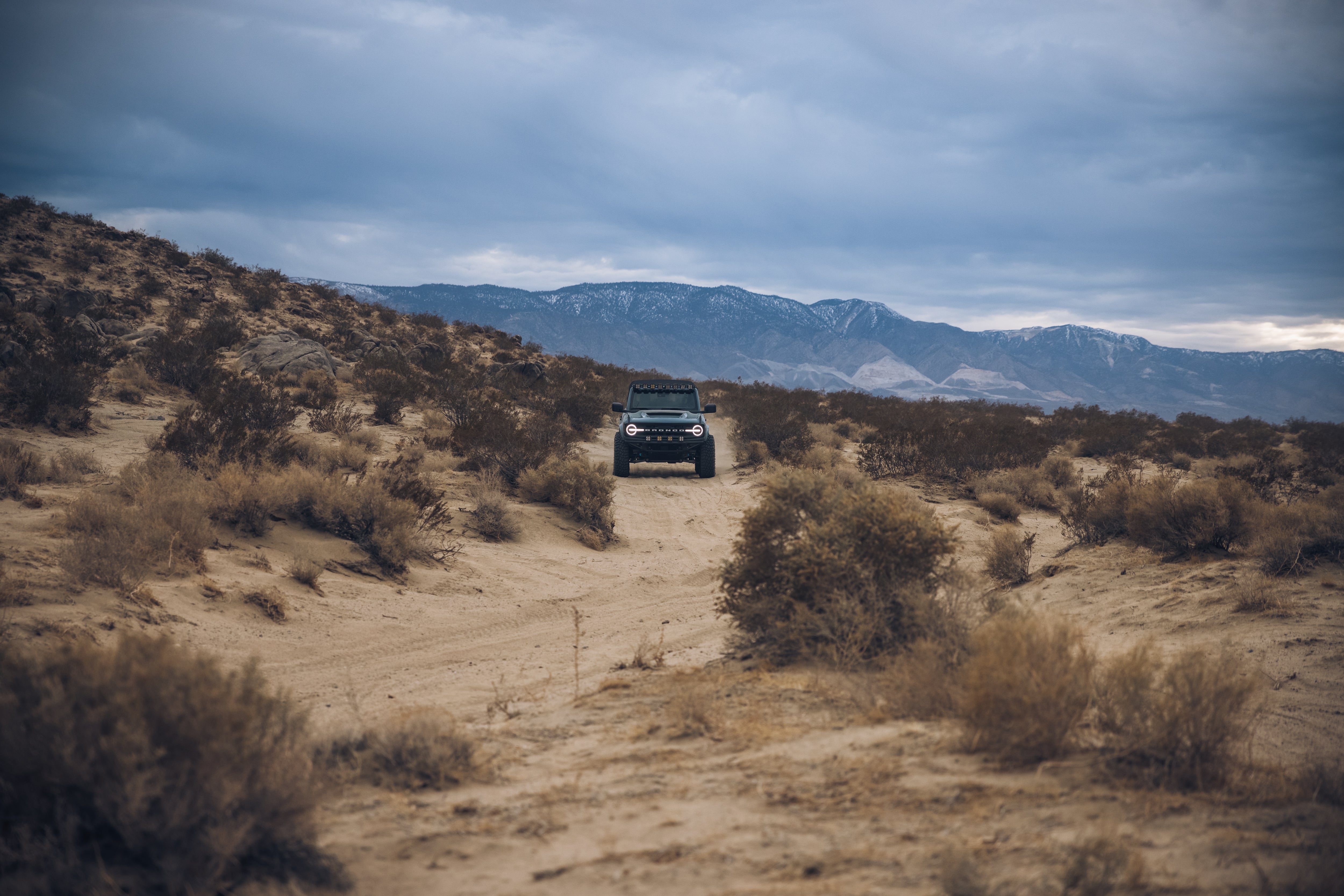 ADV Fiberglass 2021 Ford navigating a rugged desert trail with mountains in the background, showcasing offroad capability.