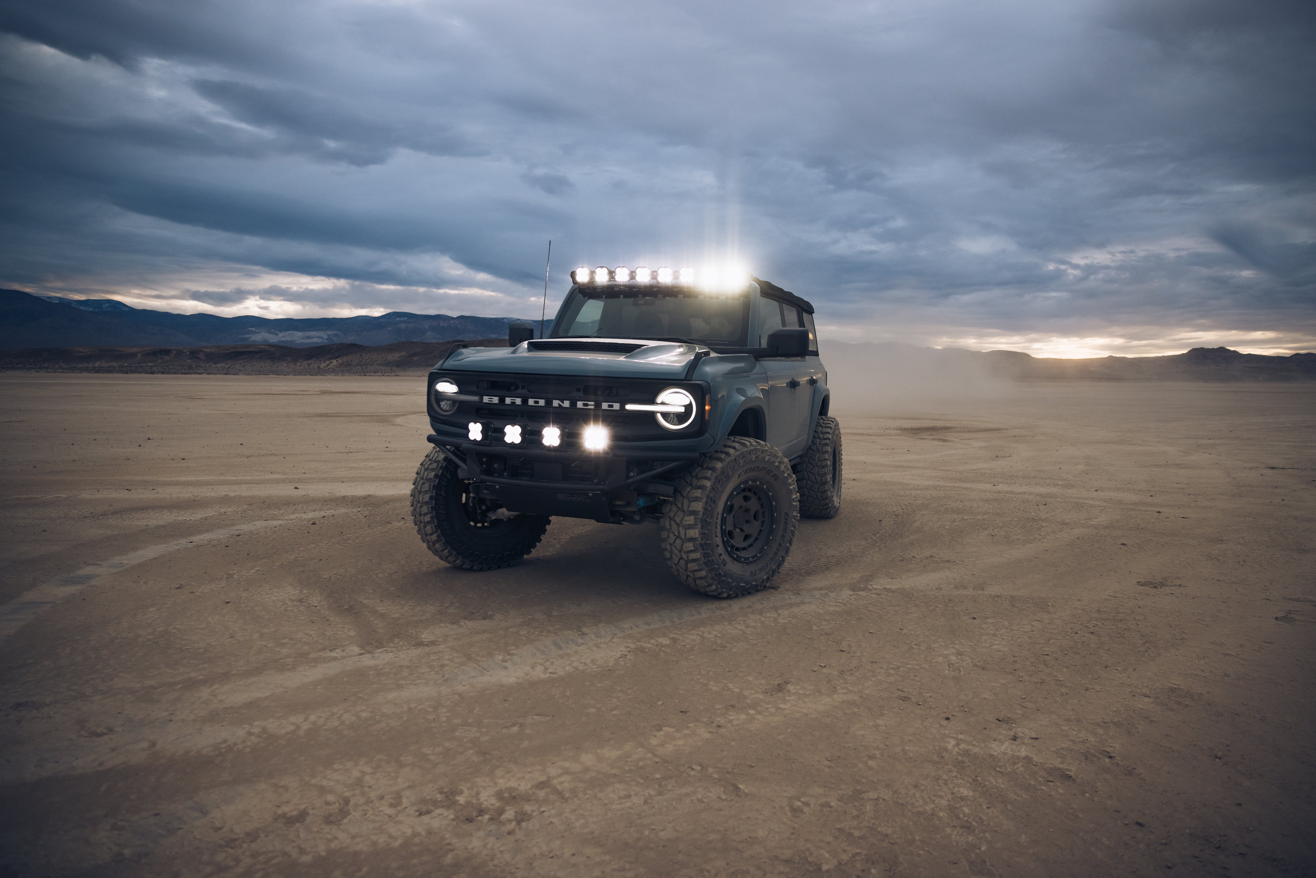ADV Fiberglass 2021 Ford Bronco equipped with off-road lights and rugged tires in a desert landscape.