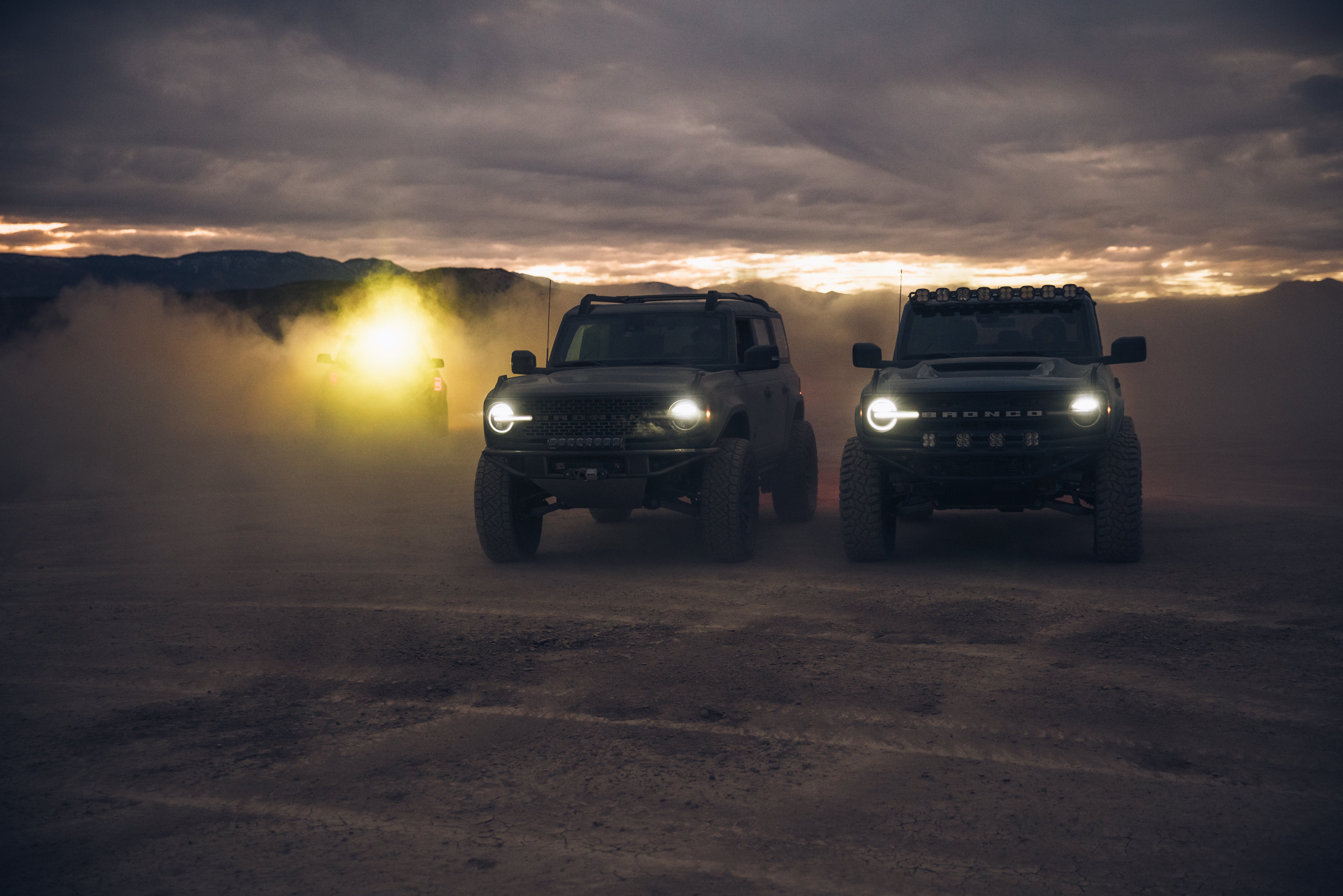 ADV Fiberglass 2021 Ford trucks in a desert setting, showcasing offroad capabilities with dust and dramatic lighting.