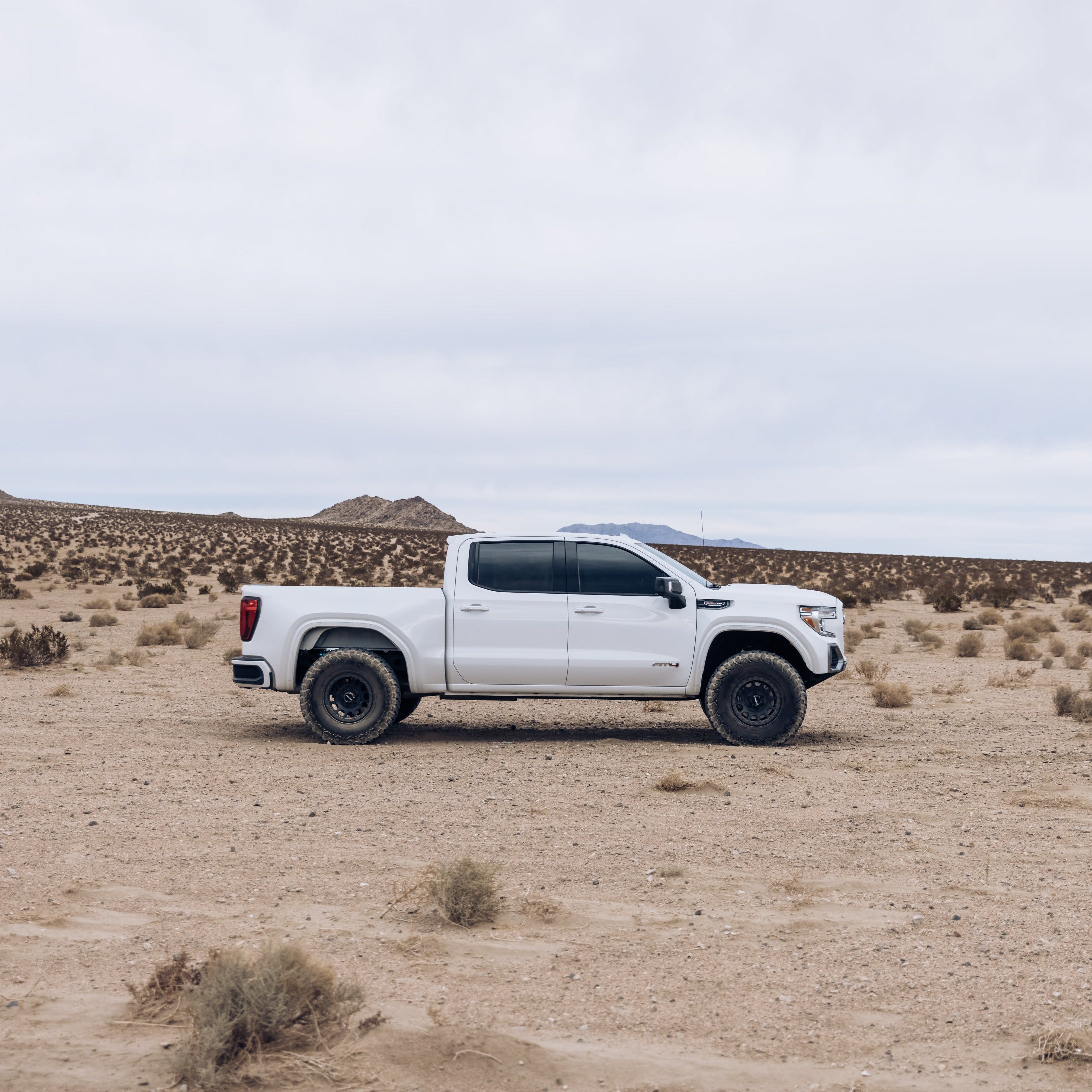 2019-2025 GMC Sierra fenders showcased on a white truck in a desert landscape, highlighting offroad capabilities.