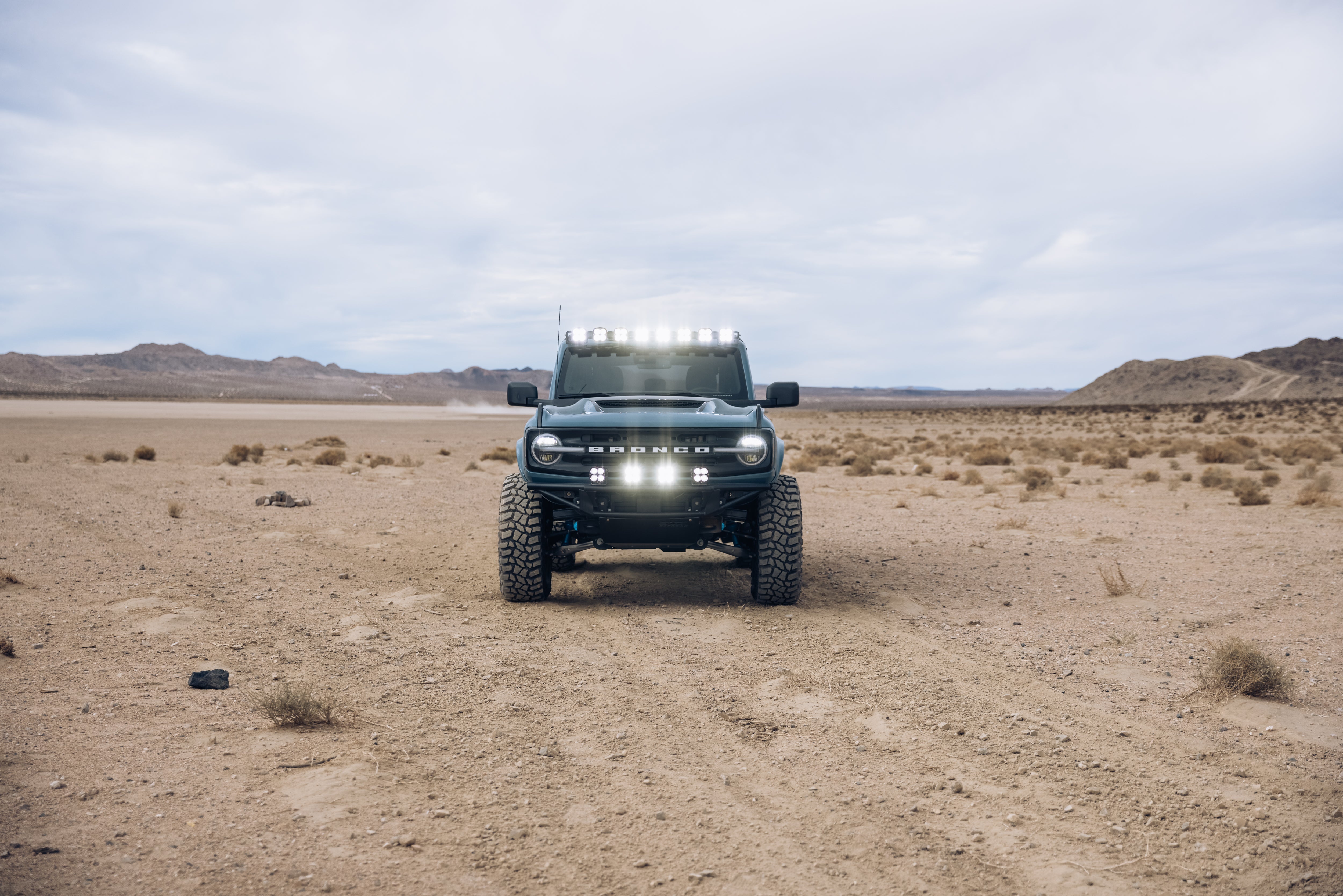 ADV Fiberglass 2021 Ford Bronco in a desert landscape, showcasing off-road capabilities with LED light bar and rugged tires.