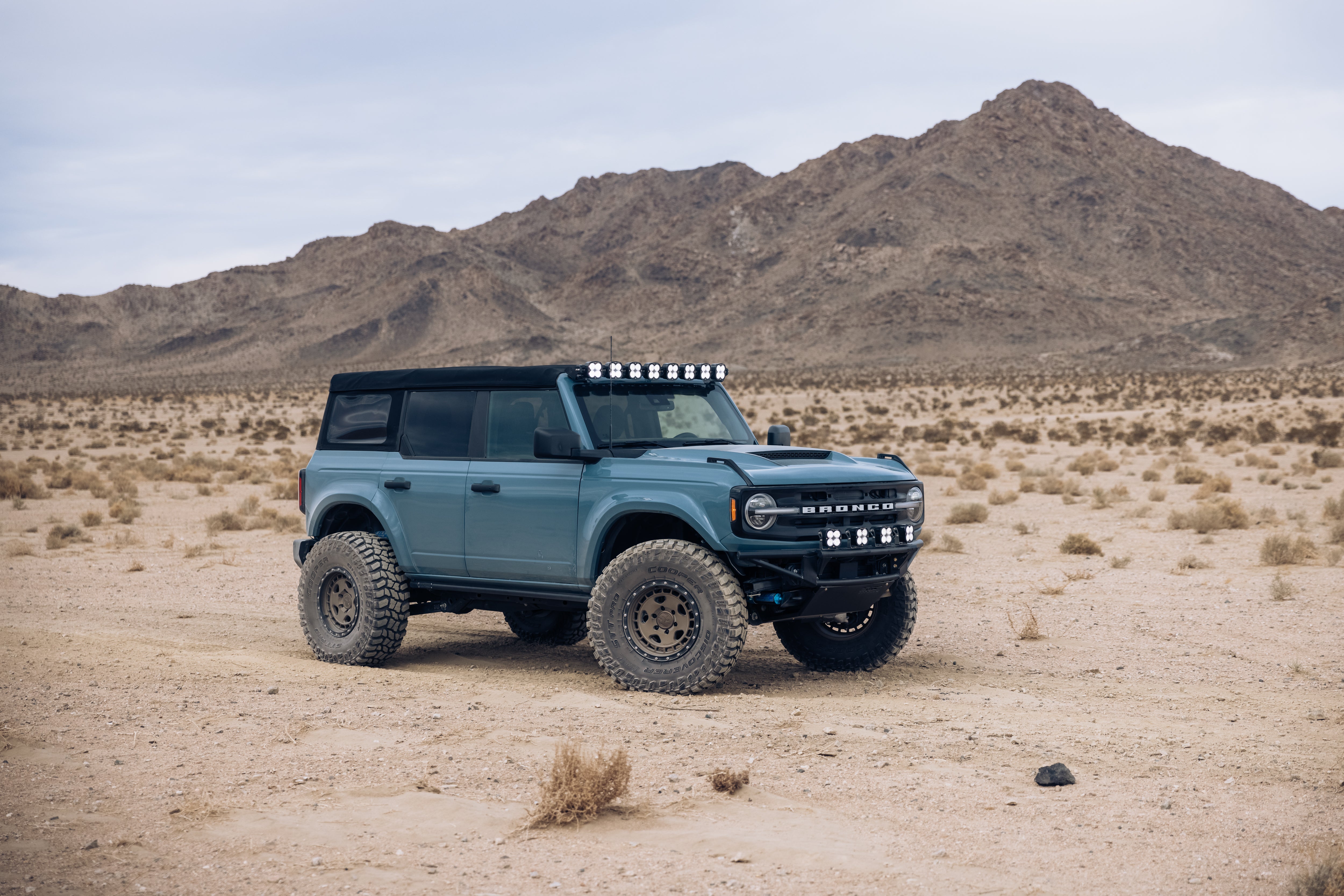 ADV Fiberglass 2021 Ford Bronco in a desert landscape, showcasing off-road capabilities with rugged tires and roof lights.