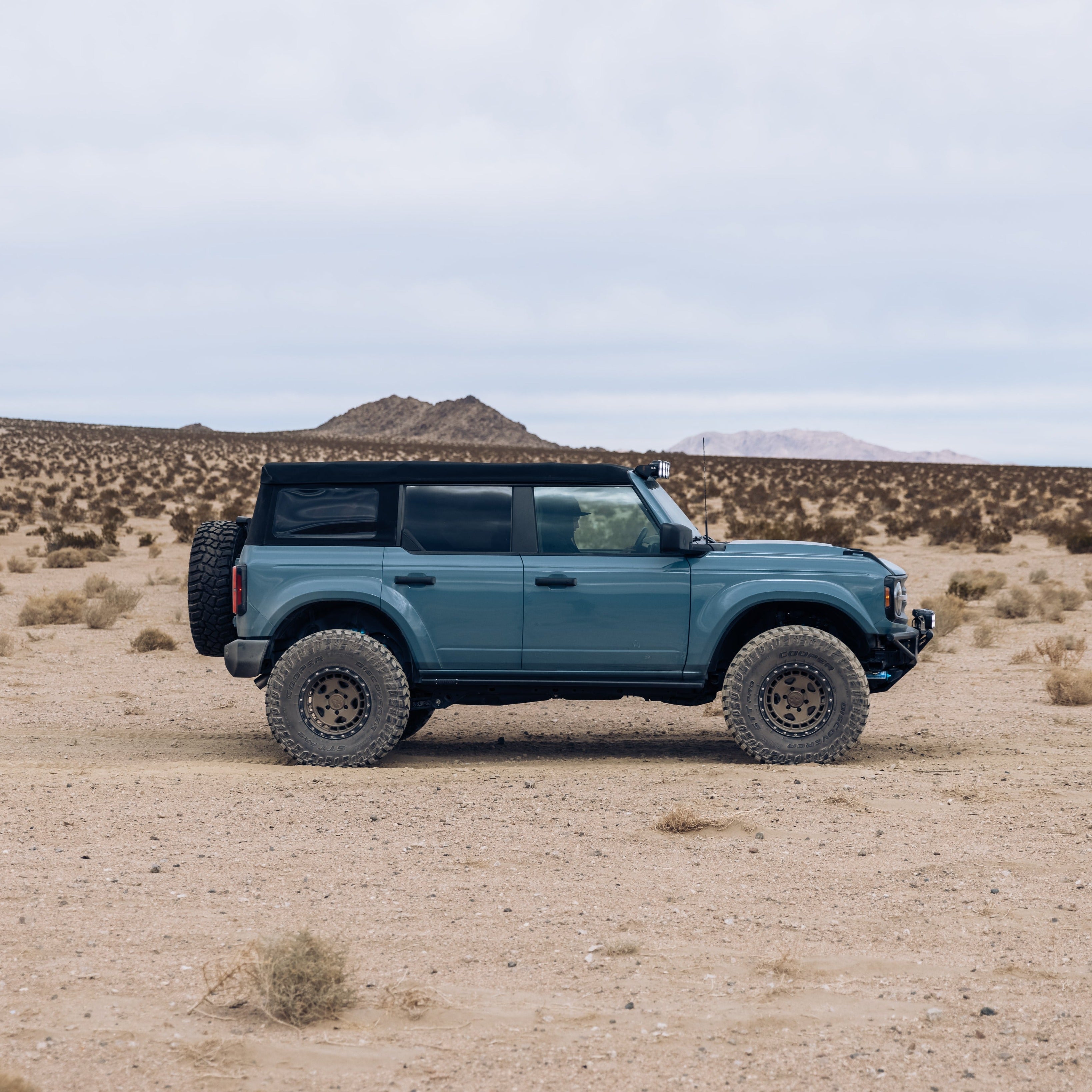 2021-2025 Ford Bronco with aftermarket fenders in a desert landscape, showcasing offroad capabilities and rugged design.