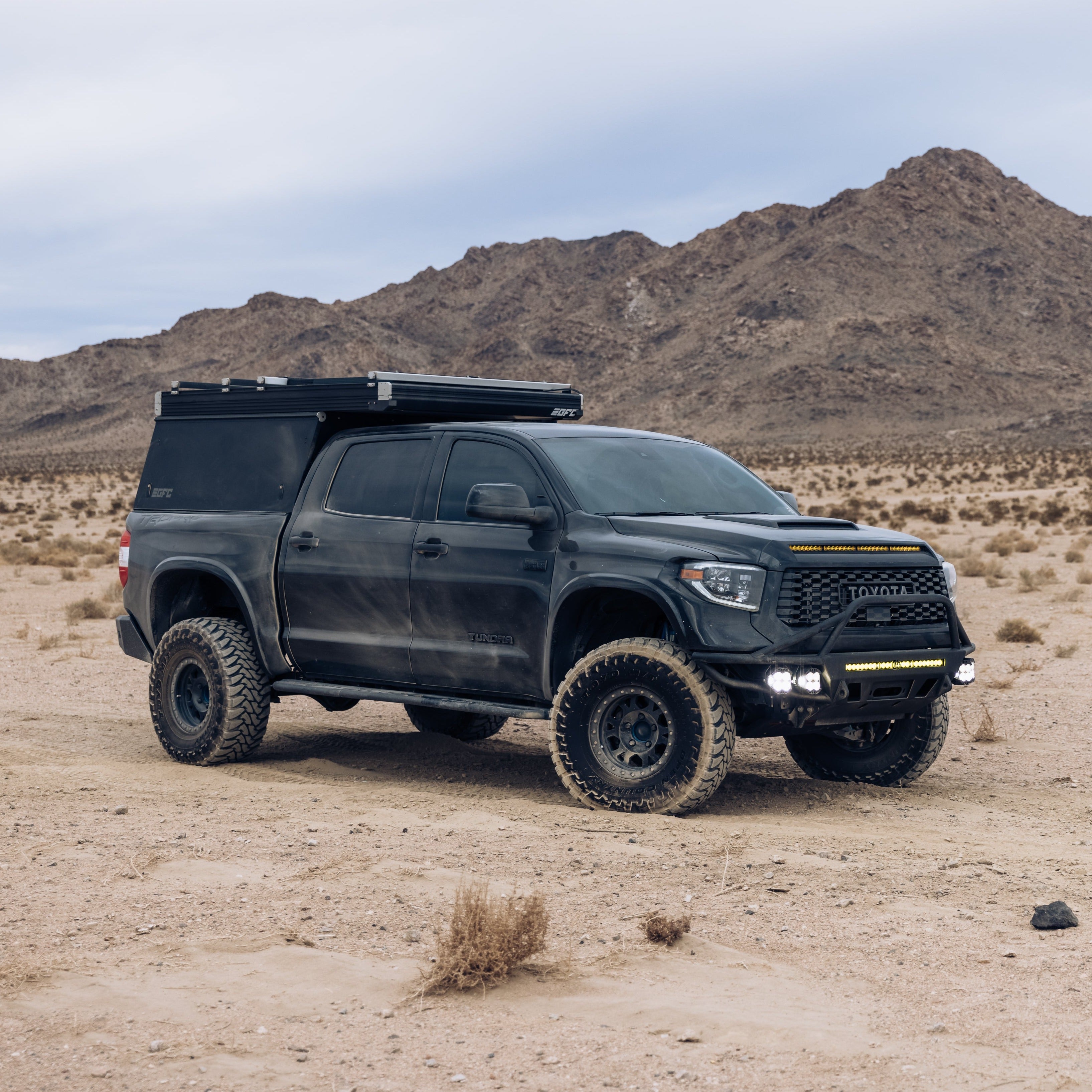 2014-2021 Toyota Tundra with aftermarket bedsides, rugged tires, and offroad accessories in a desert landscape.