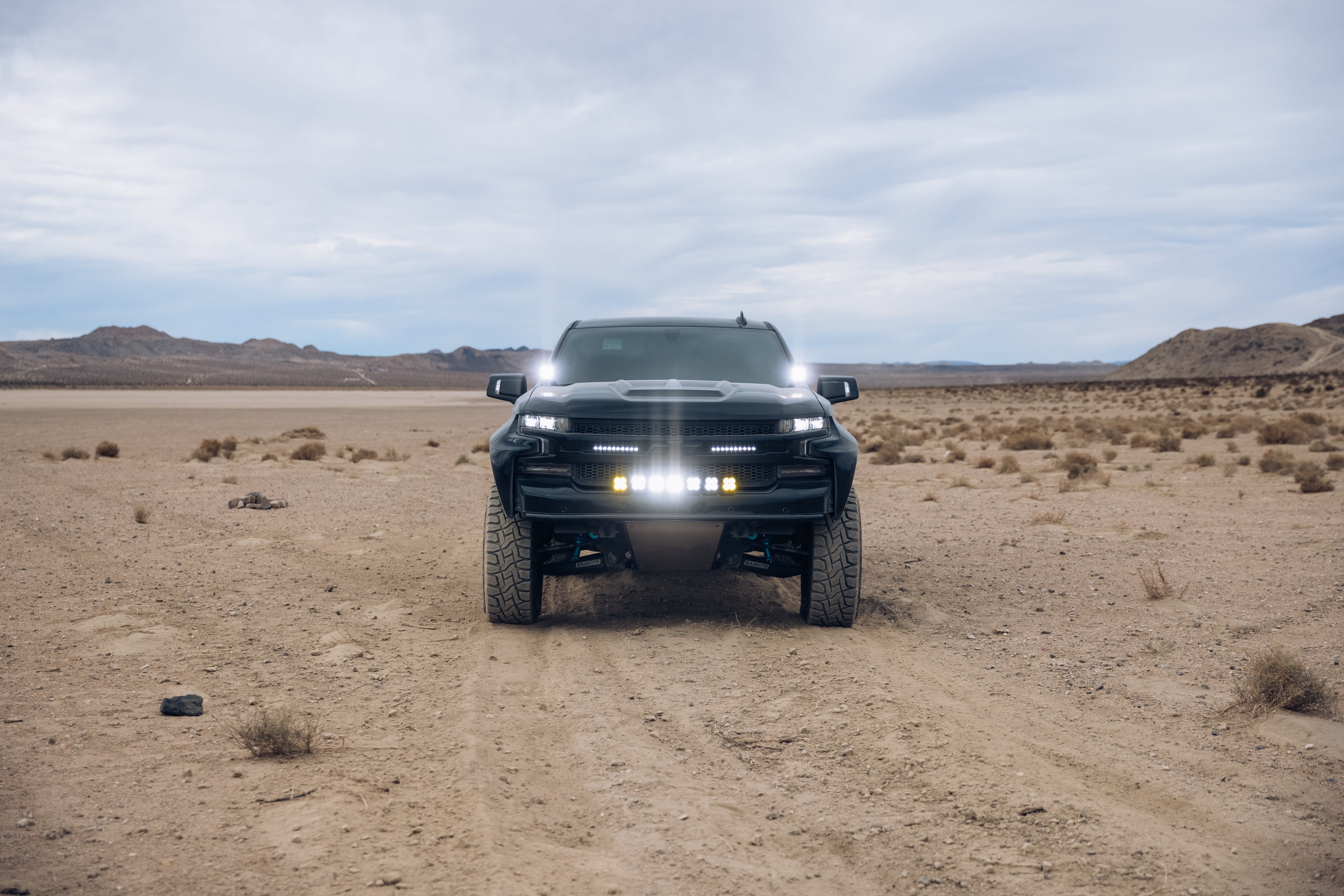 2019-2025 Chevrolet Silverado with custom bedsides parked on a rugged desert landscape, showcasing offroad capabilities.