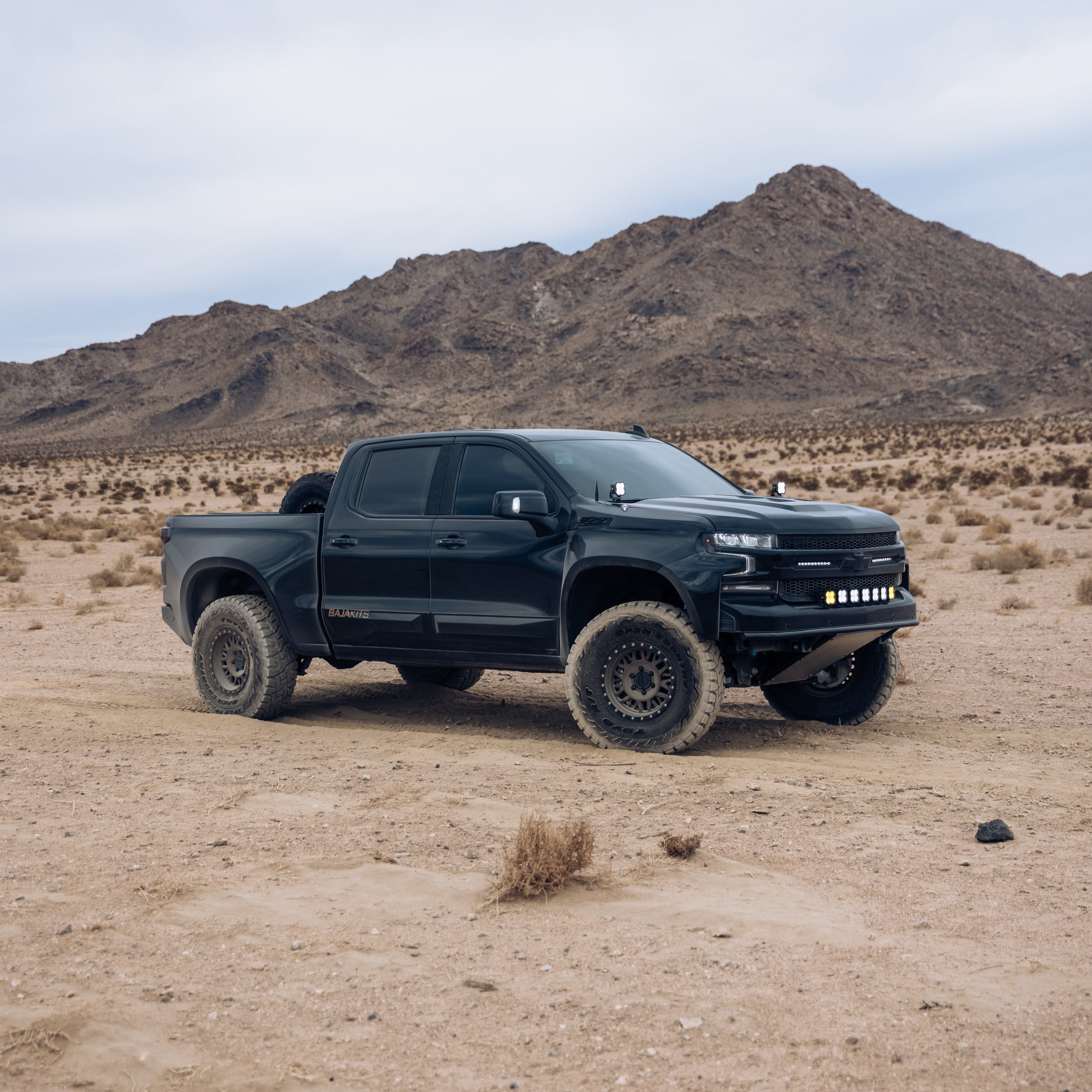 2019-2025 Chevrolet Silverado with custom bedsides in a desert landscape, showcasing offroad capabilities and rugged design.