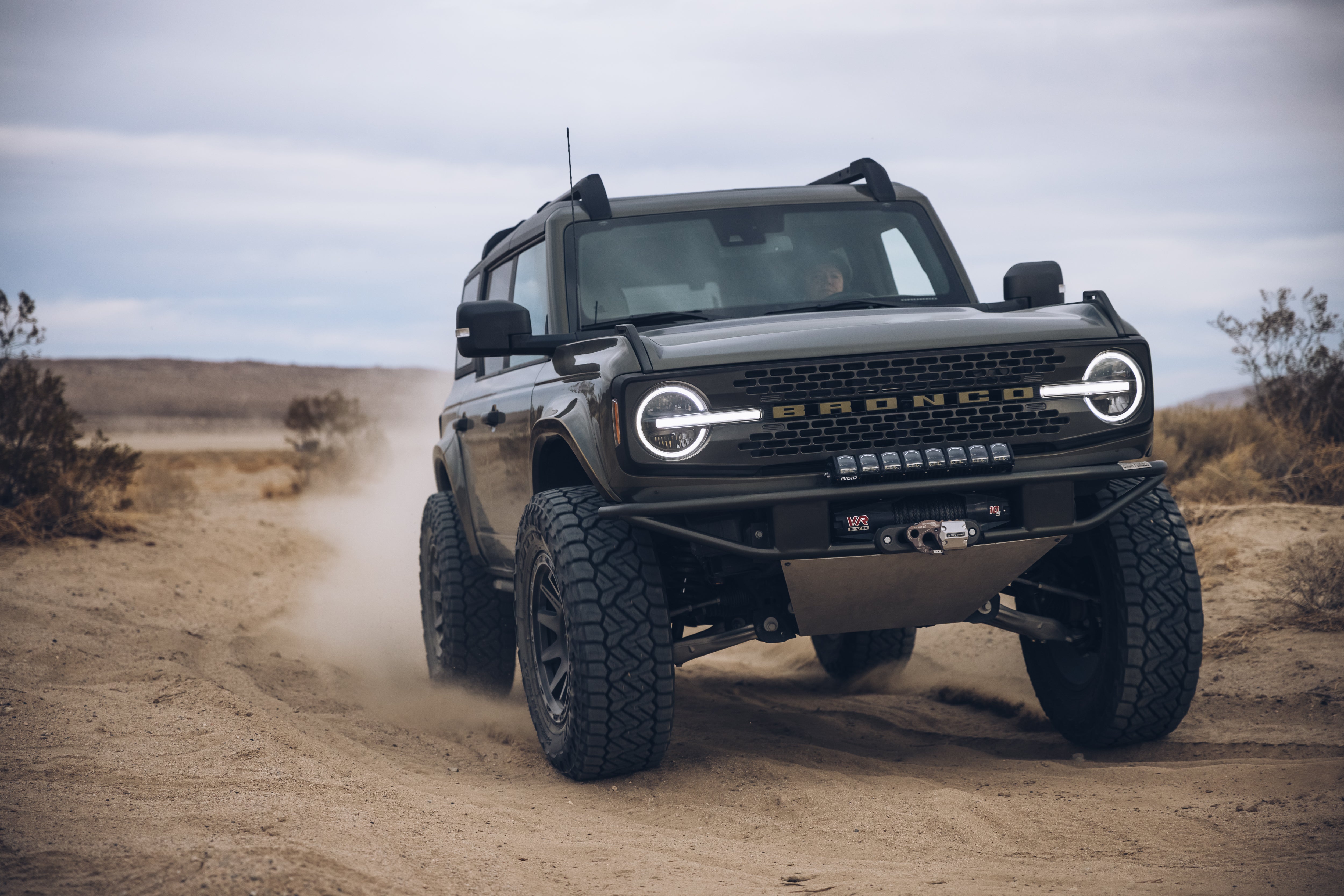 2021 Outer Banks Bronco with BAJA FORGED parts driving on a sandy off-road trail, showcasing rugged design and performance.