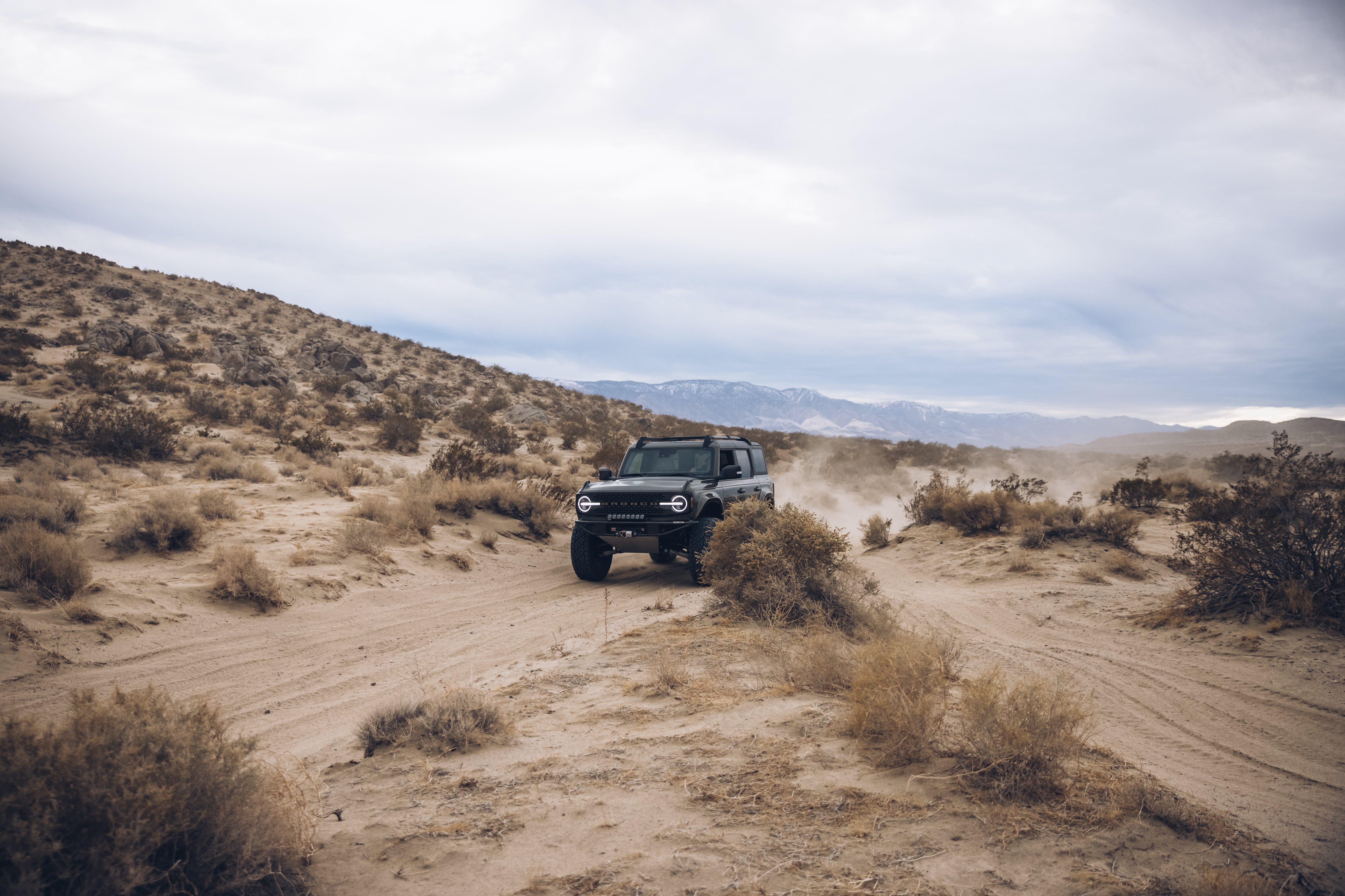 2021 Outer Banks BAJA FORGED off-road vehicle navigating a sandy desert landscape with mountains in the background.