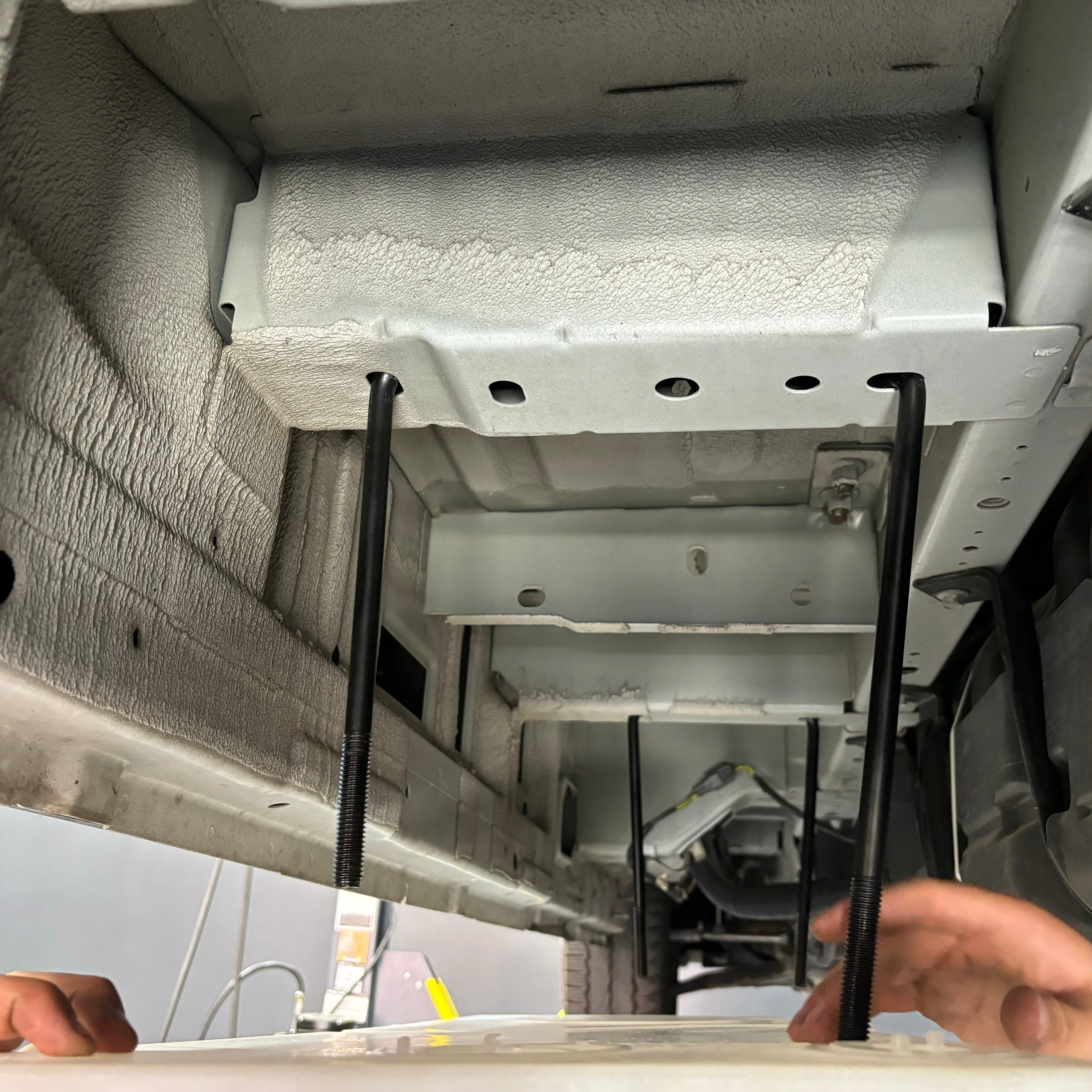 22-gallon undercarriage fresh/grey water tank installation for 2015-2025 Ford Transit, showing mounting hardware and vehicle frame.