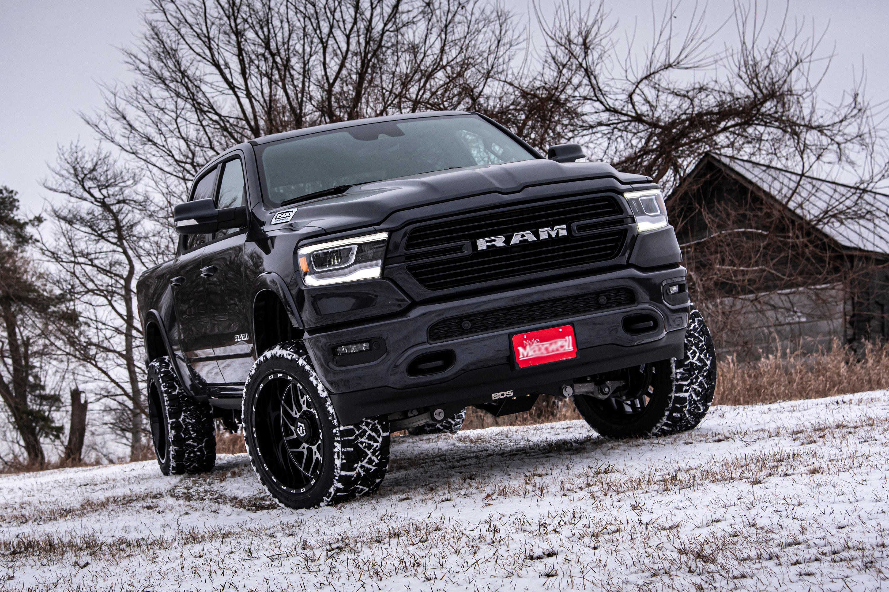Black Ram 1500 4WD with a 6-inch lift kit and FOX 2.5 coil-over suspension, parked on snow-covered ground.