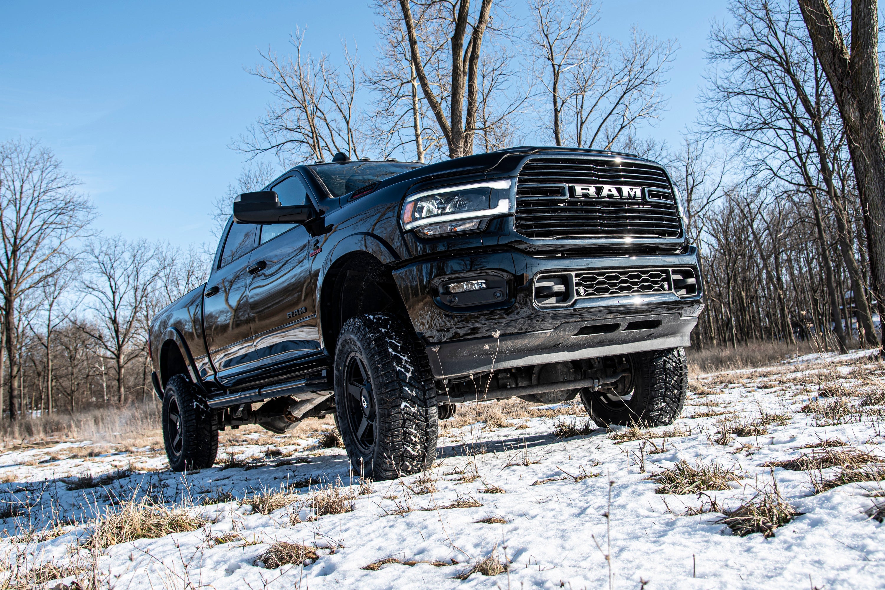 4-inch lift kit installed on a black Ram 2500 4WD diesel truck, showcasing enhanced off-road capability in a snowy landscape.