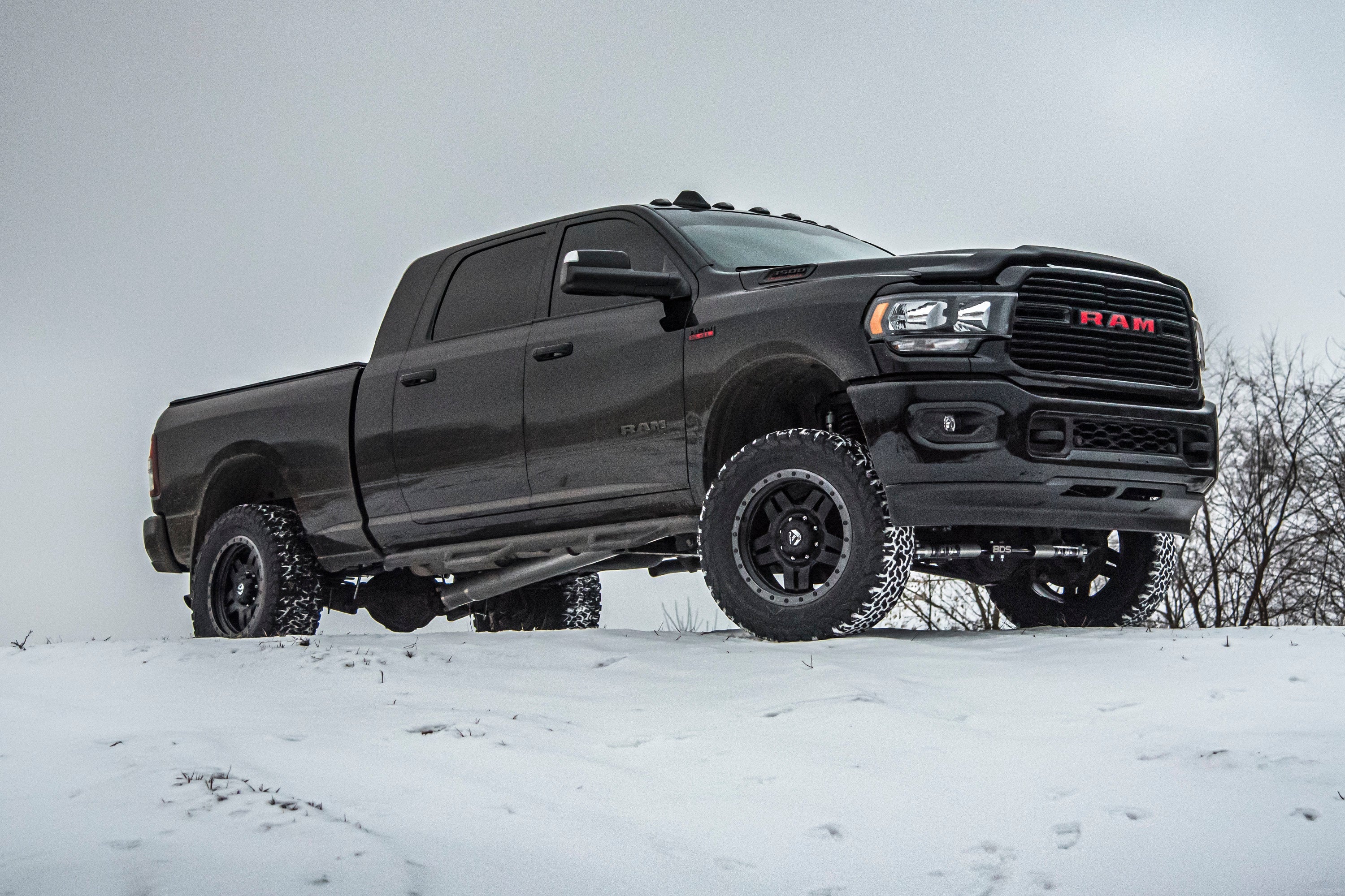 4-inch lift kit with radius arm and 2-inch rear block installed on a lifted Ram 3500 4WD diesel truck in snowy terrain.