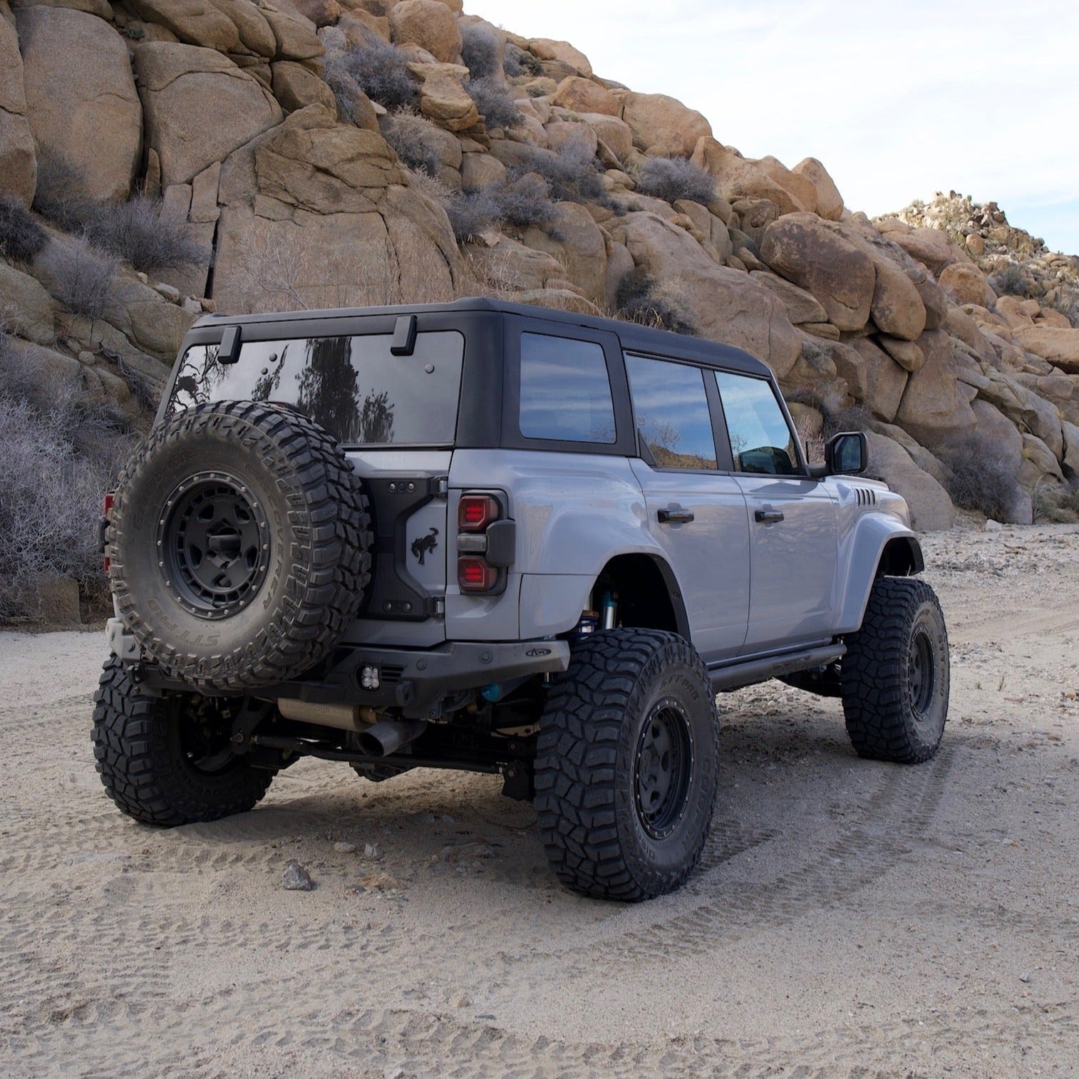 2022-2025 Ford Bronco Raptor with rear quarter kit parked on rugged terrain, showcasing offroad capabilities and design.