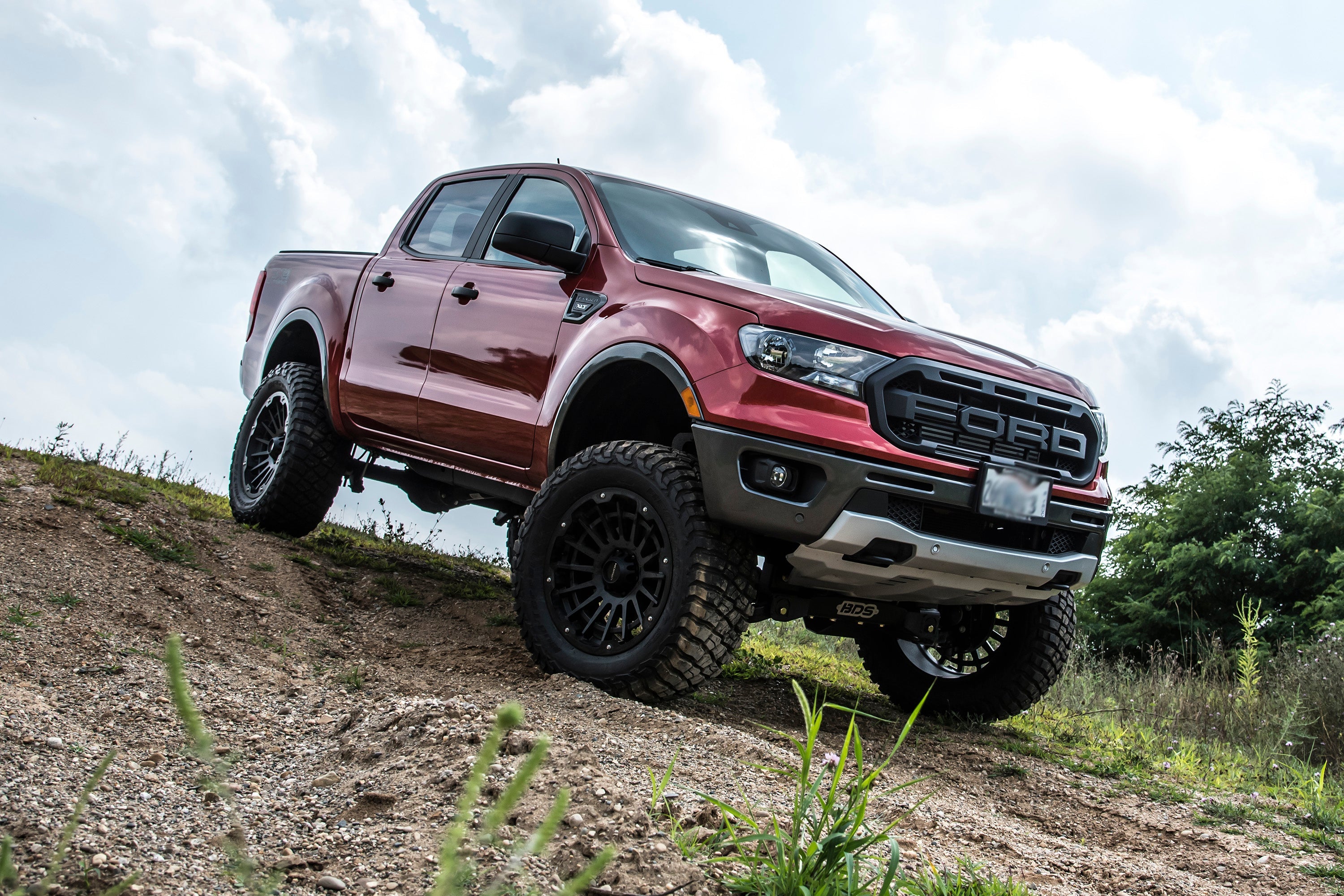 6-inch lift kit installed on a red Ford Ranger 4WD, showcasing enhanced off-road capability and rugged design.