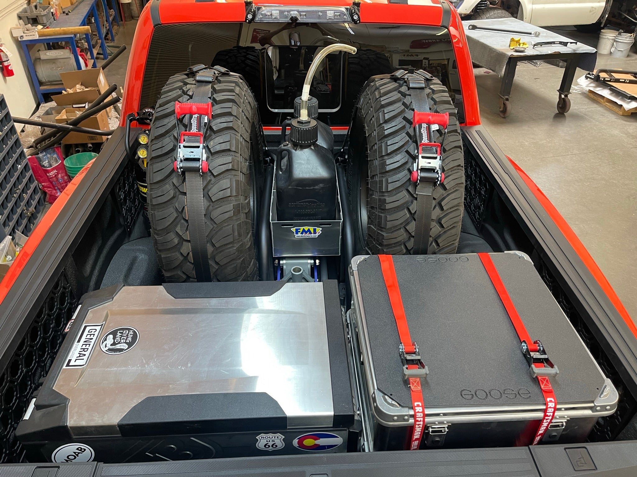 Raptor rear bed organizer with cargo slide tray, featuring secured tires and storage cases for efficient truck bed organization.
