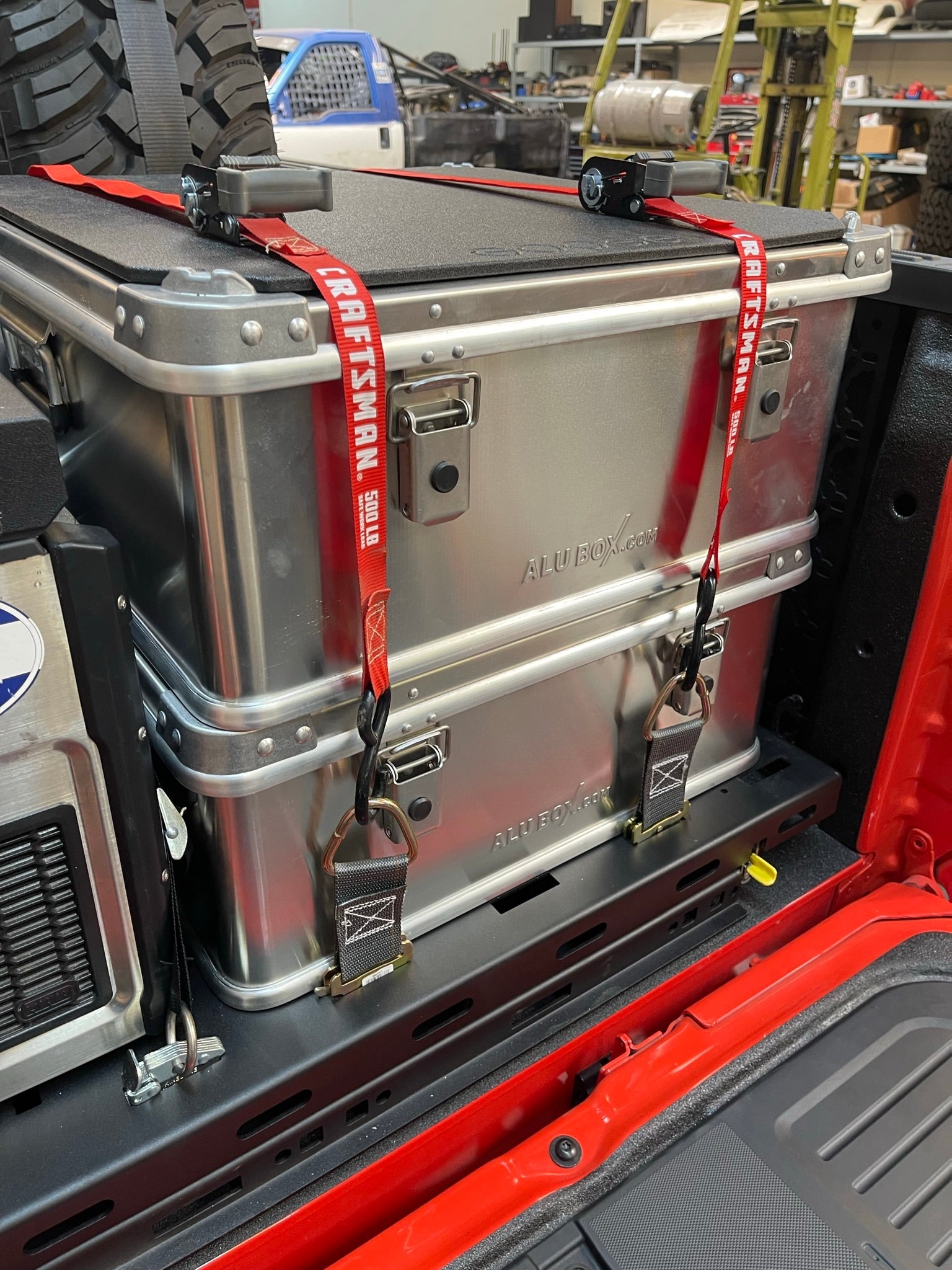 Ford Raptor modular bed organizer with slide-out cargo tray, featuring secured aluminum storage boxes and straps.
