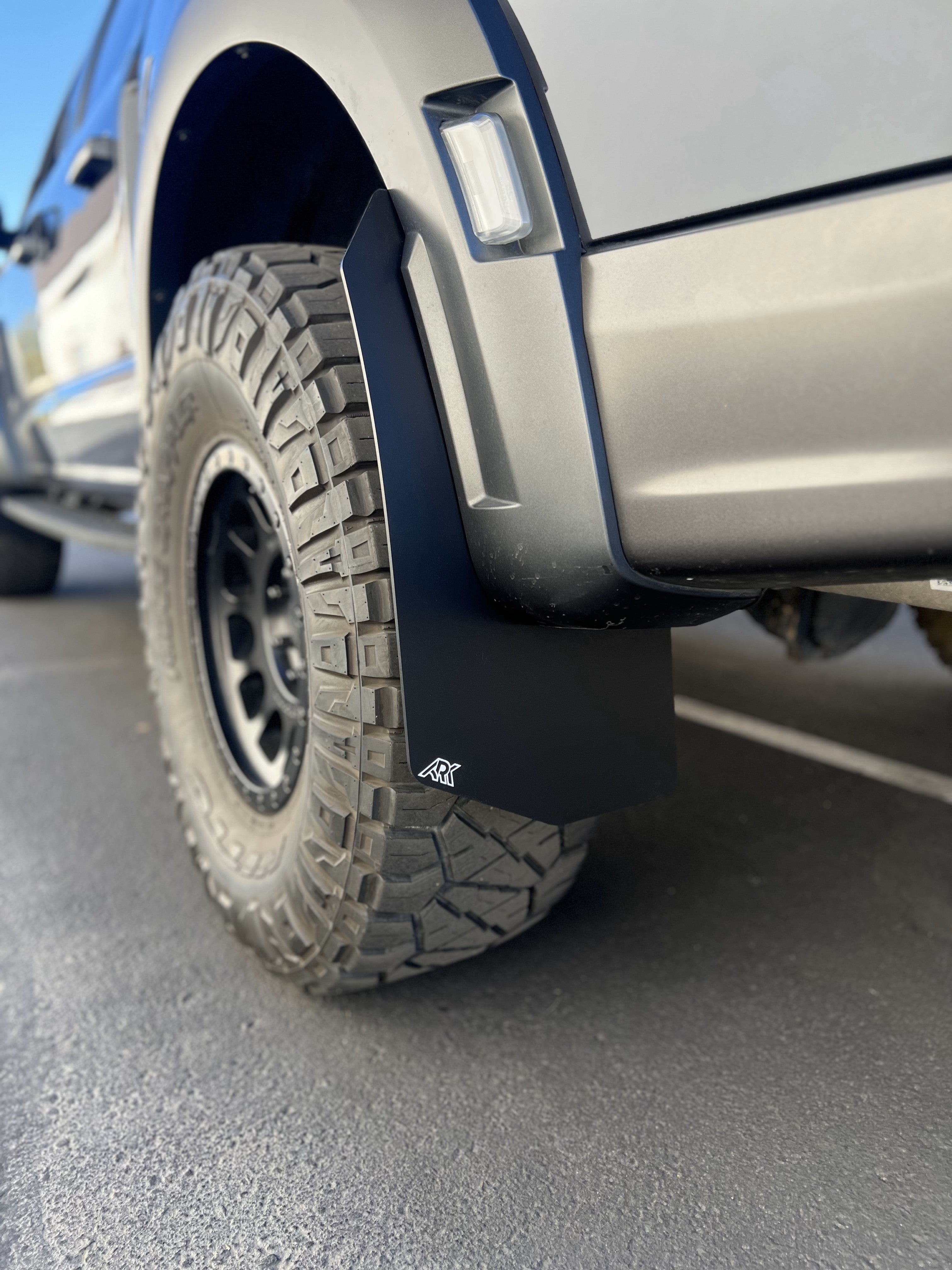 2021+ Ford Raptor mud flaps installed on a rugged tire, designed for enhanced protection and off-road performance.