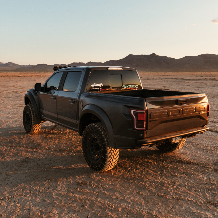 2017-2020 Ford Raptor with aftermarket bedsides, showcasing rugged off-road design in a desert landscape.