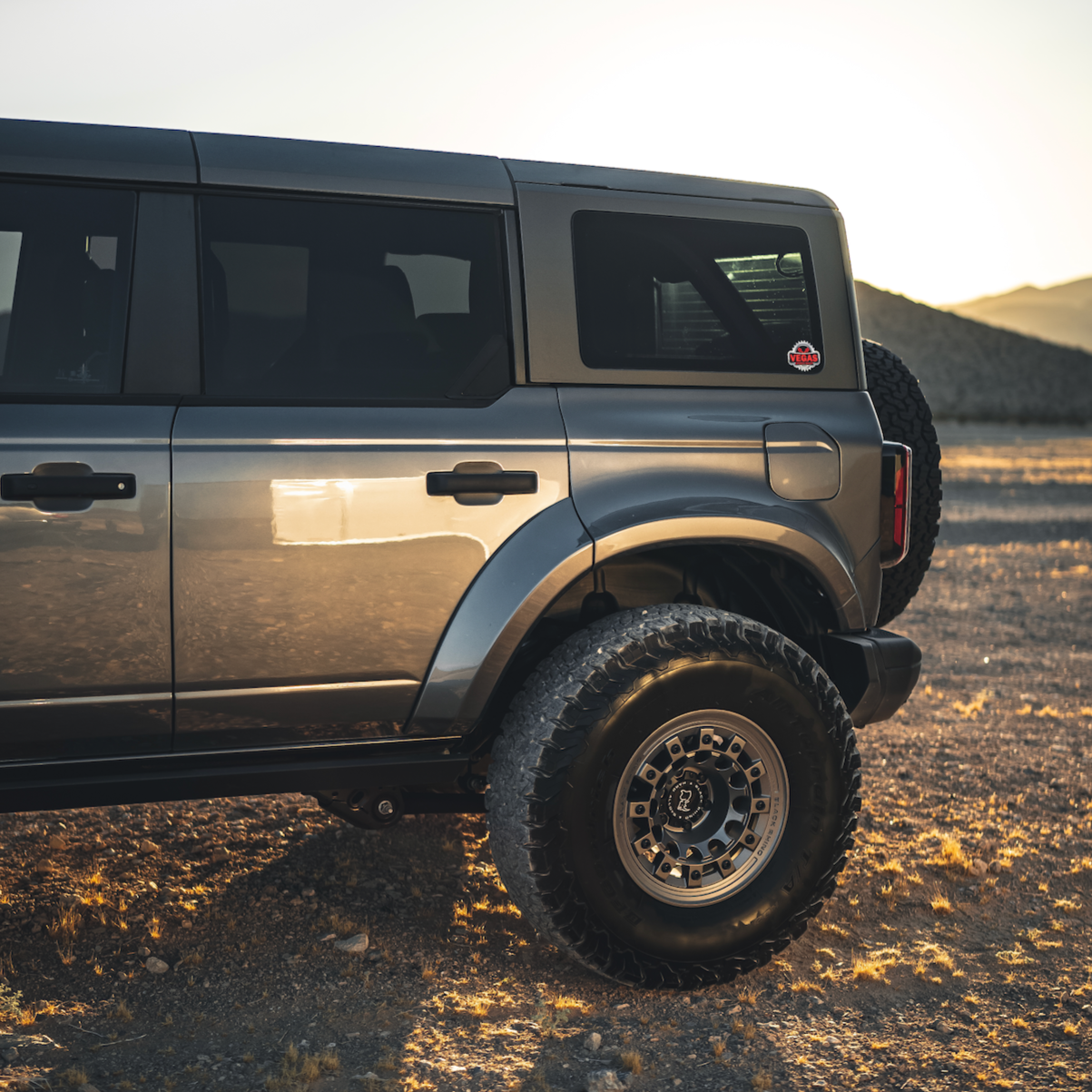 2021-2025 Ford Bronco 4-Door Rear Quarter Kit showcasing a sleek design and rugged off-road tires in a desert setting.