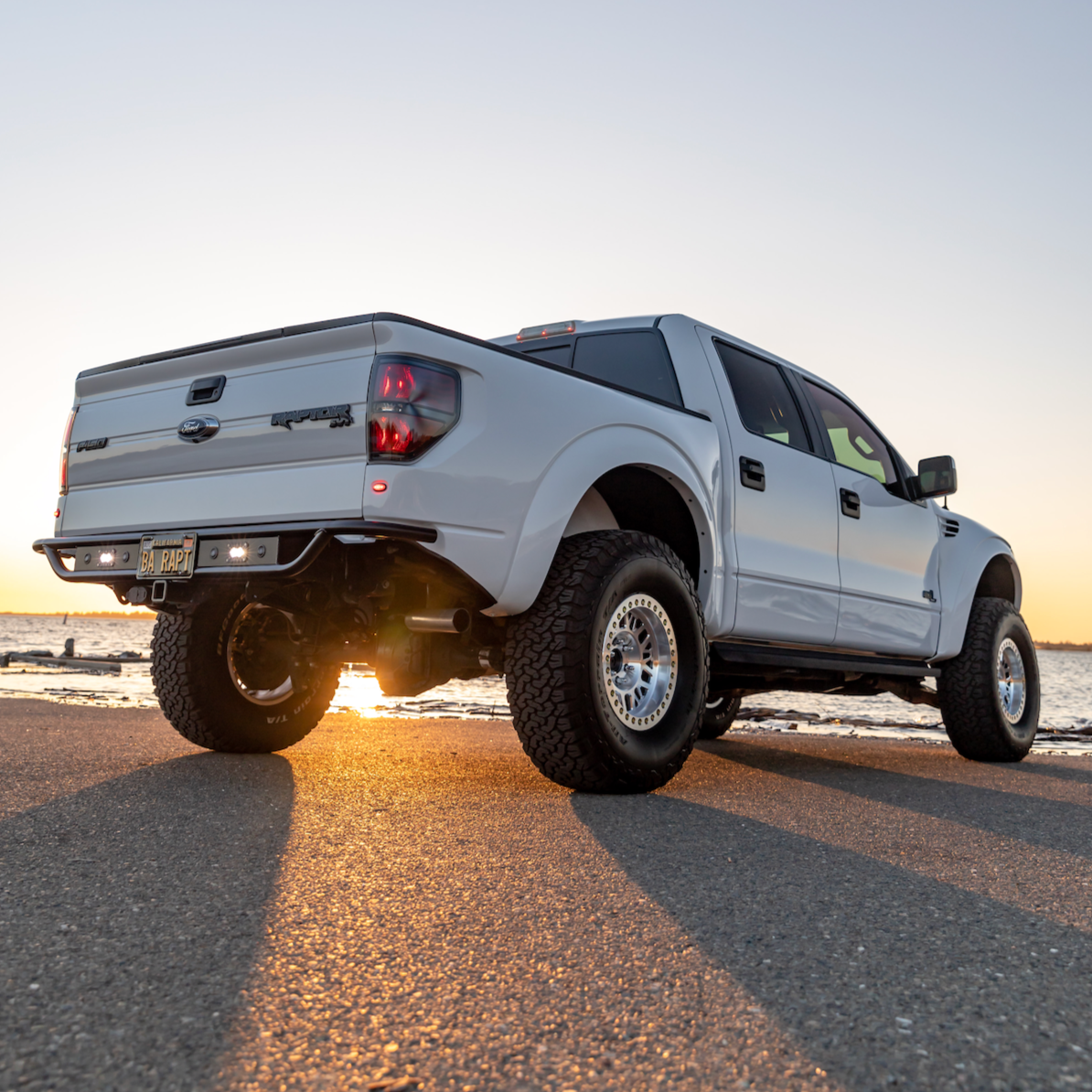 2010-2016 Ford Raptor bedsides showcased on a white truck parked by the water during sunset.