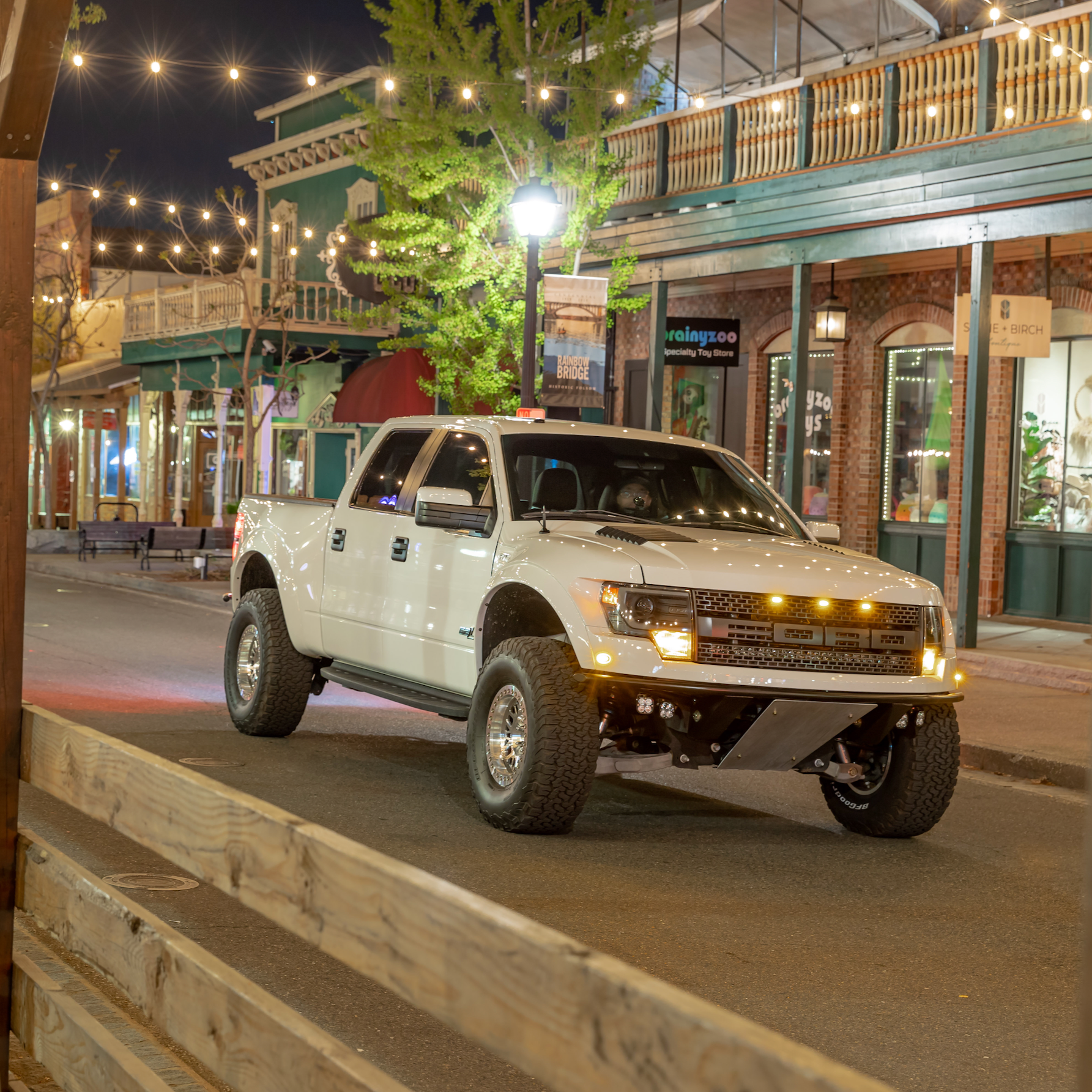 2010-2016 Ford Raptor fenders showcased on a modified truck in a vibrant urban setting at night.