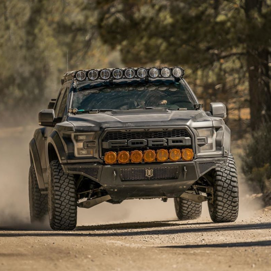 2017-2020 Ford Raptor with custom bedsides driving on a dirt road, showcasing offroad capabilities and rugged design.