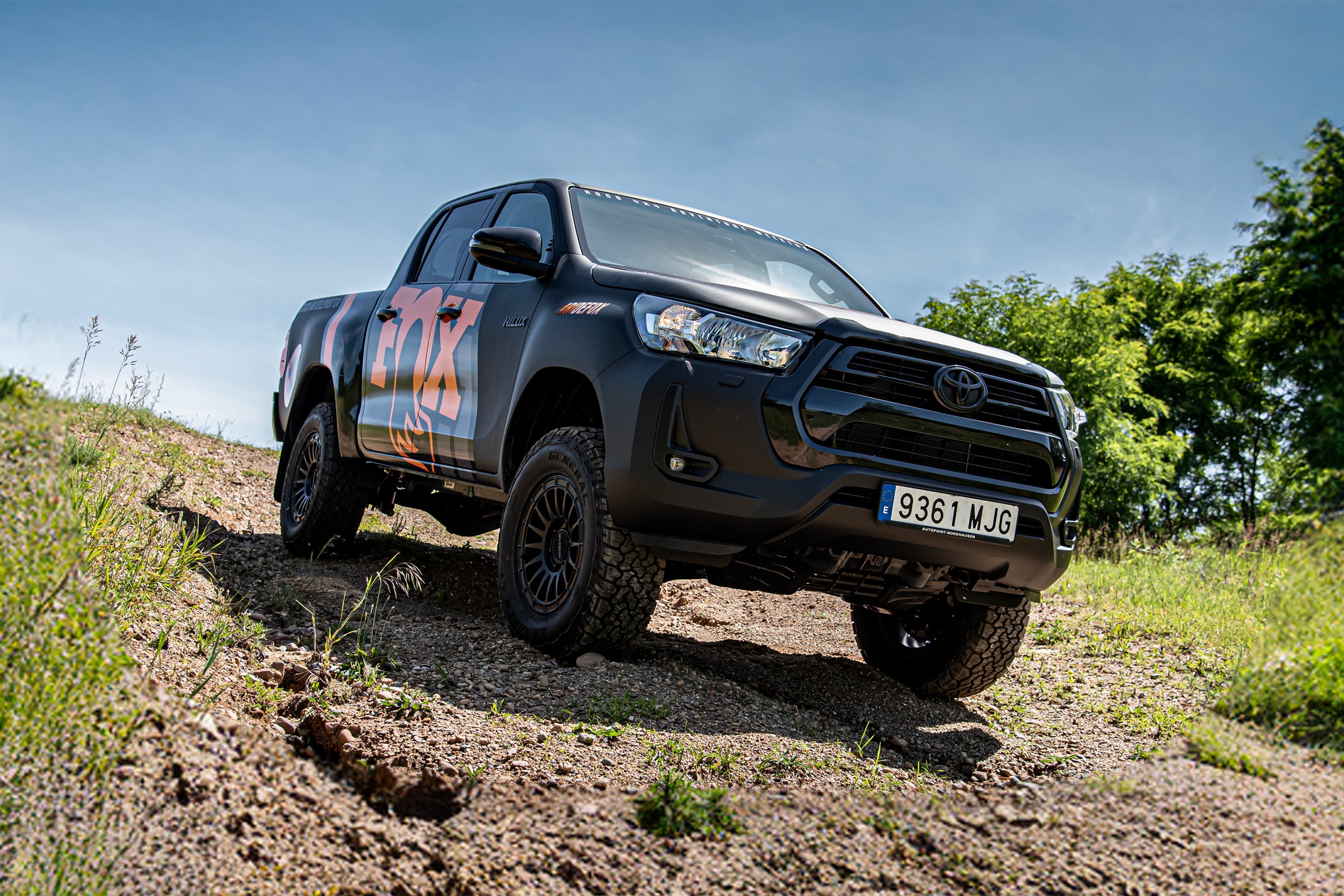Toyota Hilux with a 2-inch lift kit and FOX coil-overs, showcasing offroad capabilities on rugged terrain.