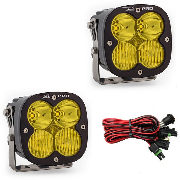 Baja Designs XL Pro LED light pair with yellow lenses, mounting brackets, and wiring harness for offroad vehicles.