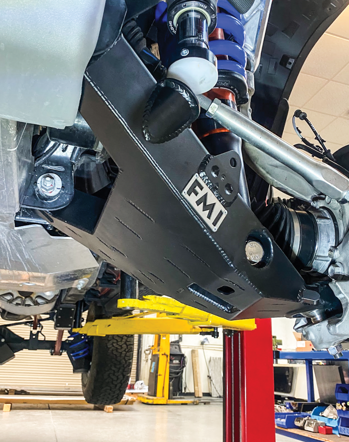 2022 Bronco Raptor mid travel front suspension kit showcasing robust components and installation setup in a workshop.